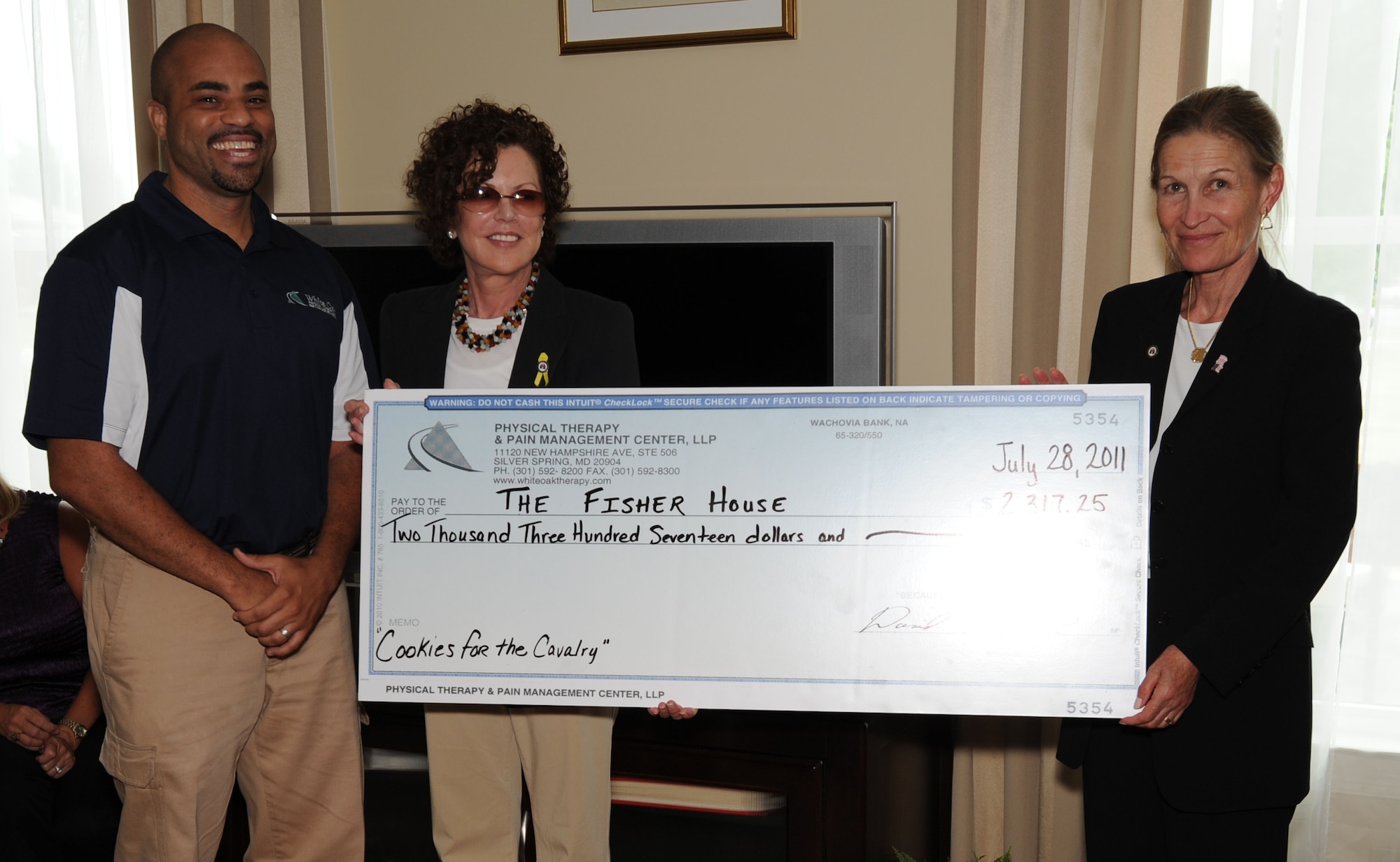 Mr. David Bullock, co-founder of White Oak Physical Therapy and Pain Management Center, Silver Springs, Md., presents a donation to the Fisher House Foundation during a ceremony at the Fisher House on Joint Base Andrews, Md. Bullock held a fundraiser called “Cookies for the Cavalry” at his office where clients brought in baked goods or made donations to raise money for the Fisher House Foundation. (U.S. Air Force photo by Staff Sgt. Christopher Ruano)