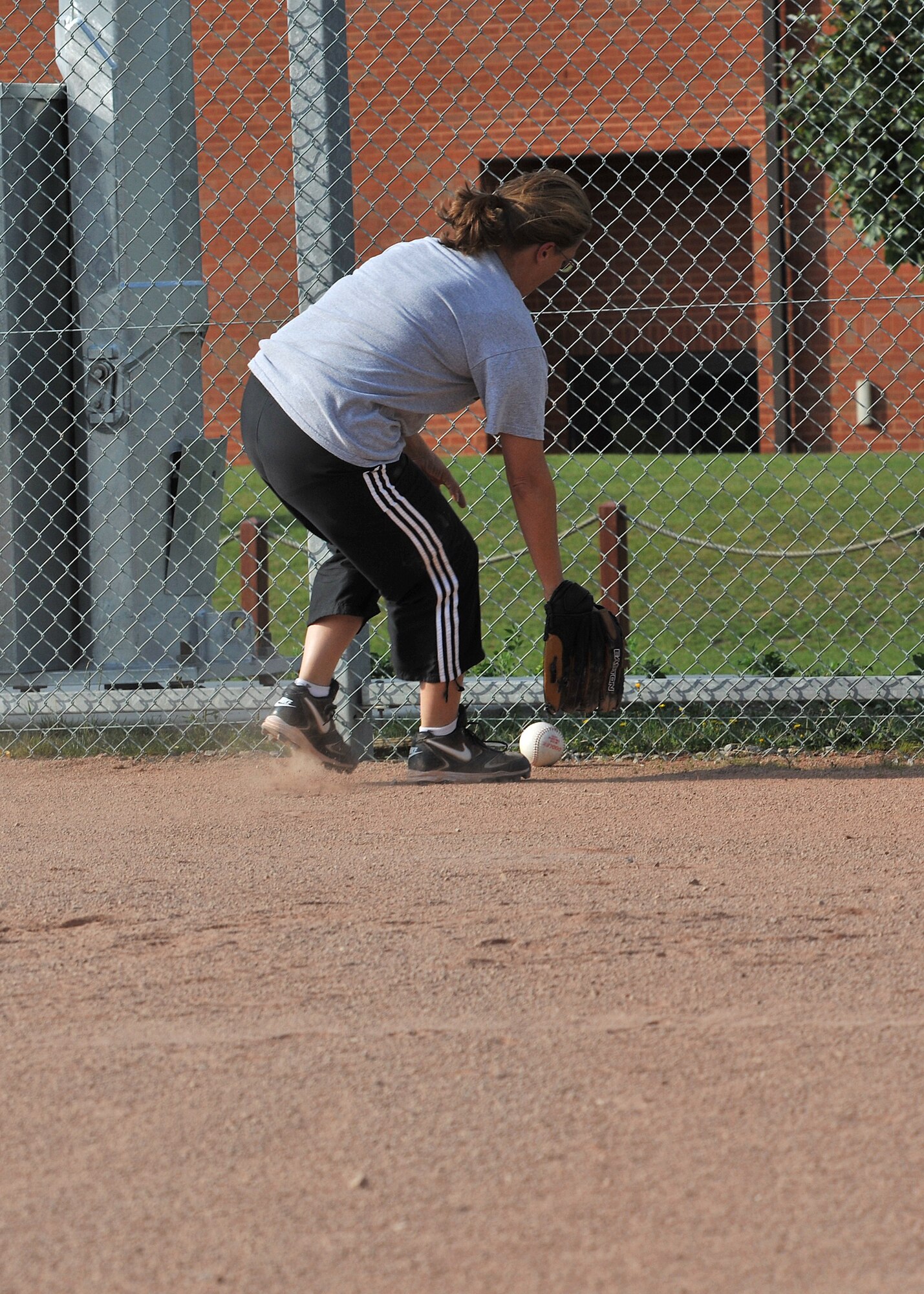 RAF MILDENHALL, England -- Mary Popson-Harberman, 100th Civil Engineer Squadron, retrieves a ball from behind home plate during the first game of the 100th Air Refueling Wing intramural softball playoffs here July 28, 2011. The intramural playoffs will run until Aug. 4 and teams are always looking for support from their units in the stands. (U.S. Air Force photo/Staff Sgt. Tabitha M. Lee)    