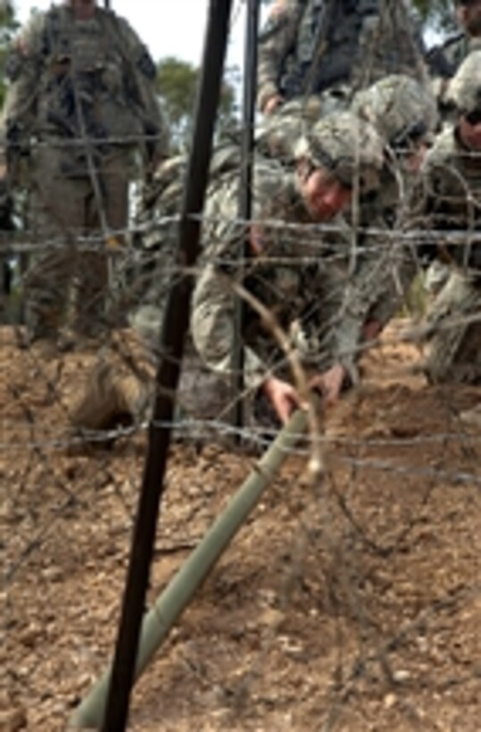 U.S. Army soldiers with the 38th Engineer Company, 4th Stryker Brigade, 2nd Infantry Division place a Bangalore explosive to clear a barbed wire obstacle during Talisman Sabre 2011 at the Shoalwater Bay Training Area in Queensland, Australia, on July 15, 2011.  Talisman Sabre is a combined biennial exercise between the U.S. and Australian militaries designed to enhance both nations.  