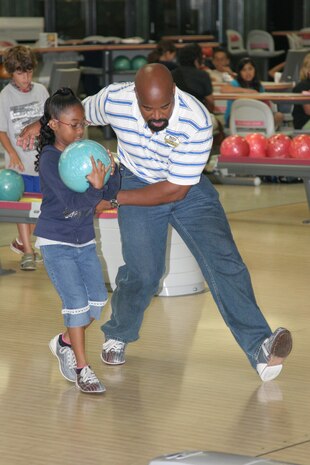 John R. Baltazar III, Marine Corps Community Services youth sports coordinator, instructs Riana E. Coffman, 8, on proper form and technique during the bowling camp as part of the MCCS Command sports camp at the Strike Zone here Monday. The camp sought to teach children the fundamentals, etiquette, and techniques of bowling. The camp lasted from Monday-Wednesday. The last camp for the summer will be volleyball from Thursday-Friday.