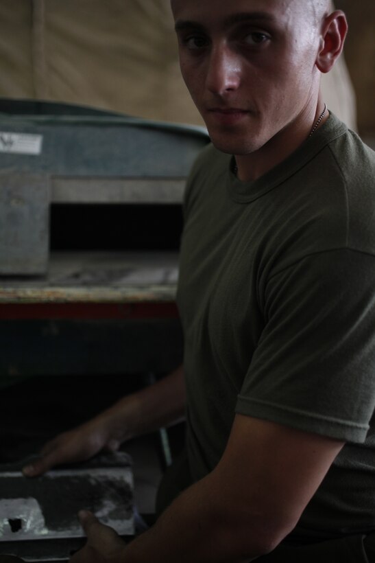 Cpl. Leonard R. Knudsen Jr. holds a steel rail used to attach cargo to the hull of a CH-53E Super Stallion in the hangar of Marine Heavy Helicopter Squadron 464 in Camp Bastion, Afghanistan, Aug. 2. On a recent mission, enemy small-arms fire penetrated the underside of the aircraft and went through the railing. Knudsen, an airframe mechanic with the squadron and a native of Chicago, was tasked to repair the hole. Having been in Afghanistan less than two weeks, he said seeing the bullet hole gave him new perspective on his role in the war.