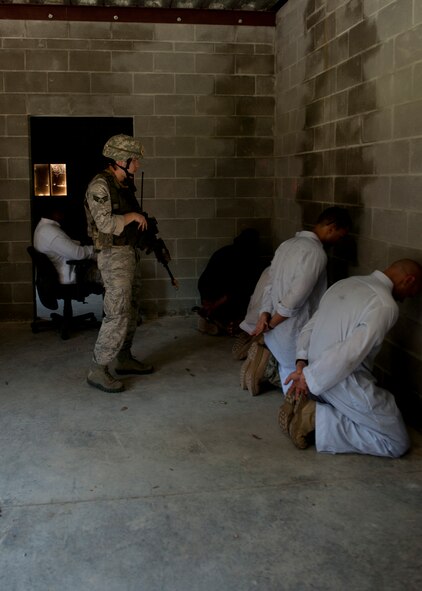 U.S. Air Force Senior Airman James Lewis, 823rd Base Defense Squadron fireteam member, apprehends possible opposing forces while clearing a building at the military operations in urban terrain village training facility during the squad leadership course at Moody Air Force Base, Ga., July 29, 2011. Airmen participated in this strategic and tactical training to apply it to real world situations and one day lead a squad of their own. (U.S. Air Force photo by Airman 1st Class Joshua Green/Released)
