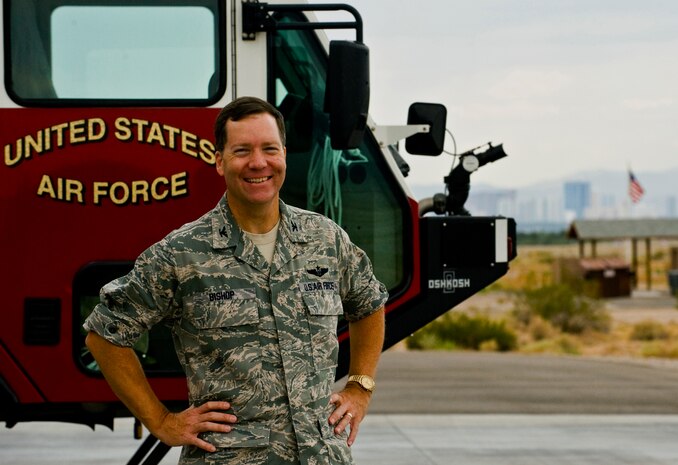 U.S. Air Force Col. Darren Bishop, 99th Air Base Wing Mission Support Group commander, stands in front of a firetruck July 26, 2011, at Nellis Air Force Base, Nev.  The 99 MSG provides mission-ready Airmen to combatant commanders, as well as infrastructure and services to support the Nellis and Creech Air Force Bases' warfighters. (U.S. Air Force photo by Airman 1st Class George Goslin/Released)