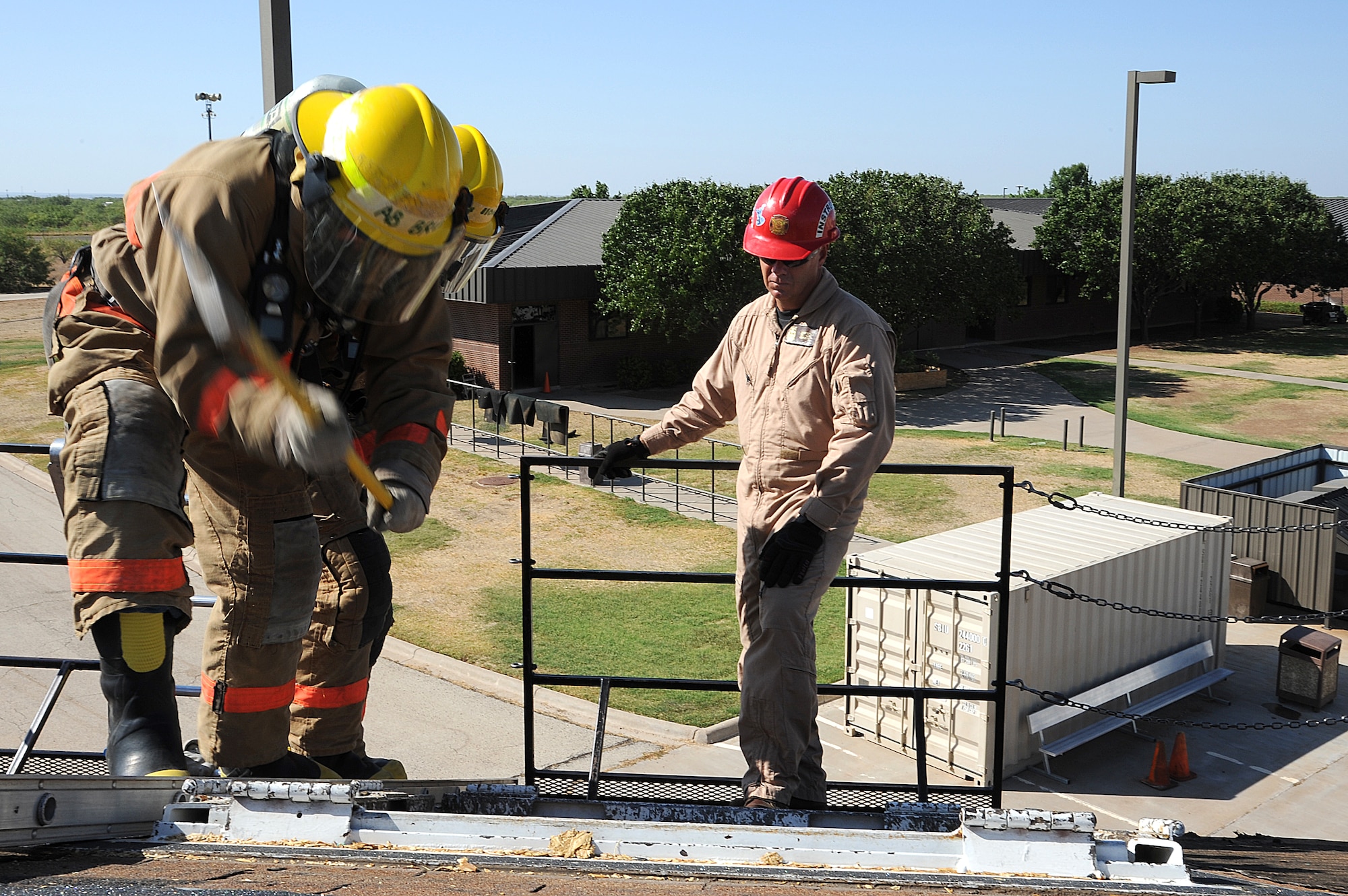 GOODFELLOW AIR FORCE BASE, Texas--Students from the 312th Training Squadron create a hole in the roof of a building at the Louis F. Garland Fire Academy July 28. The drill consists of climbing to the top of the building followed by breaching into the roof to allow smoke ventilation from the fire.  (U.S. Air Force photo/Airman 1st Class Michael Smith)