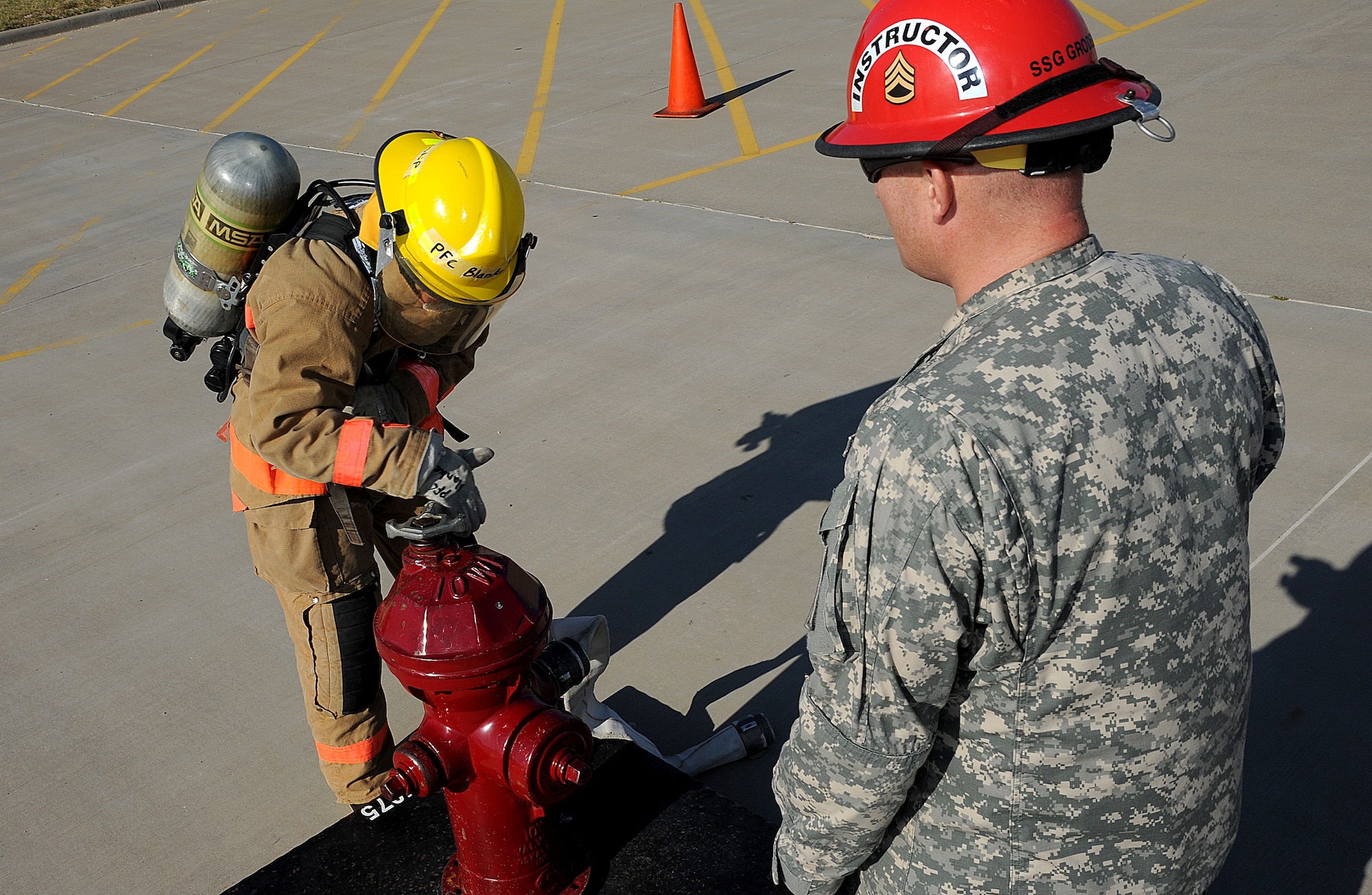 GOODFELLOW AIR FORCE BASE, Texas—Army Pfc. Jacob Blankenship, 312th Training Squadron student, releases the water from a mock fire hydrant, as Staff Sgt. Aaron Groder, 312th Training Squadron instructor, times him July 28. This drill is used to assure that the students know how to use the tools provided for them even in a time of urgency. (Air Force photo/ Airman 1st Class Michael Smith)