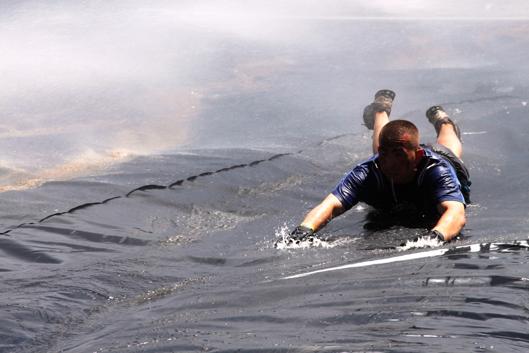 310th Space Wing member Tech. Sgt. Alejandro Sanchez slides down the Greased Lightening obstacle at the Tough Mudder in Avon, Colo. on June 26. Sanchez, one of the team organizers, helped guide the 310th's challengers to the finish line, leaving no Airman behind. (U.S. Air Force photo/Tech. Sgt. Scott P. Farley)