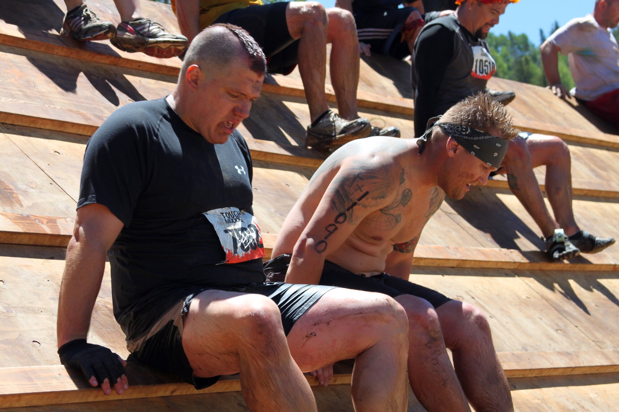 310th Space Wing member Staff Sgt. Aaron Hunt and 460th Space member Senior Airman Josh Slaton rest after making it over the Everest obstacle at the Tough Mudder in Avon, Colo. on June 26. It was a team effort for Hunt and Slaton to reach the top and make it over the slippery giant quarter pipe. (U.S. Air Force photo/Tech. Sgt. Scott P. Farley)