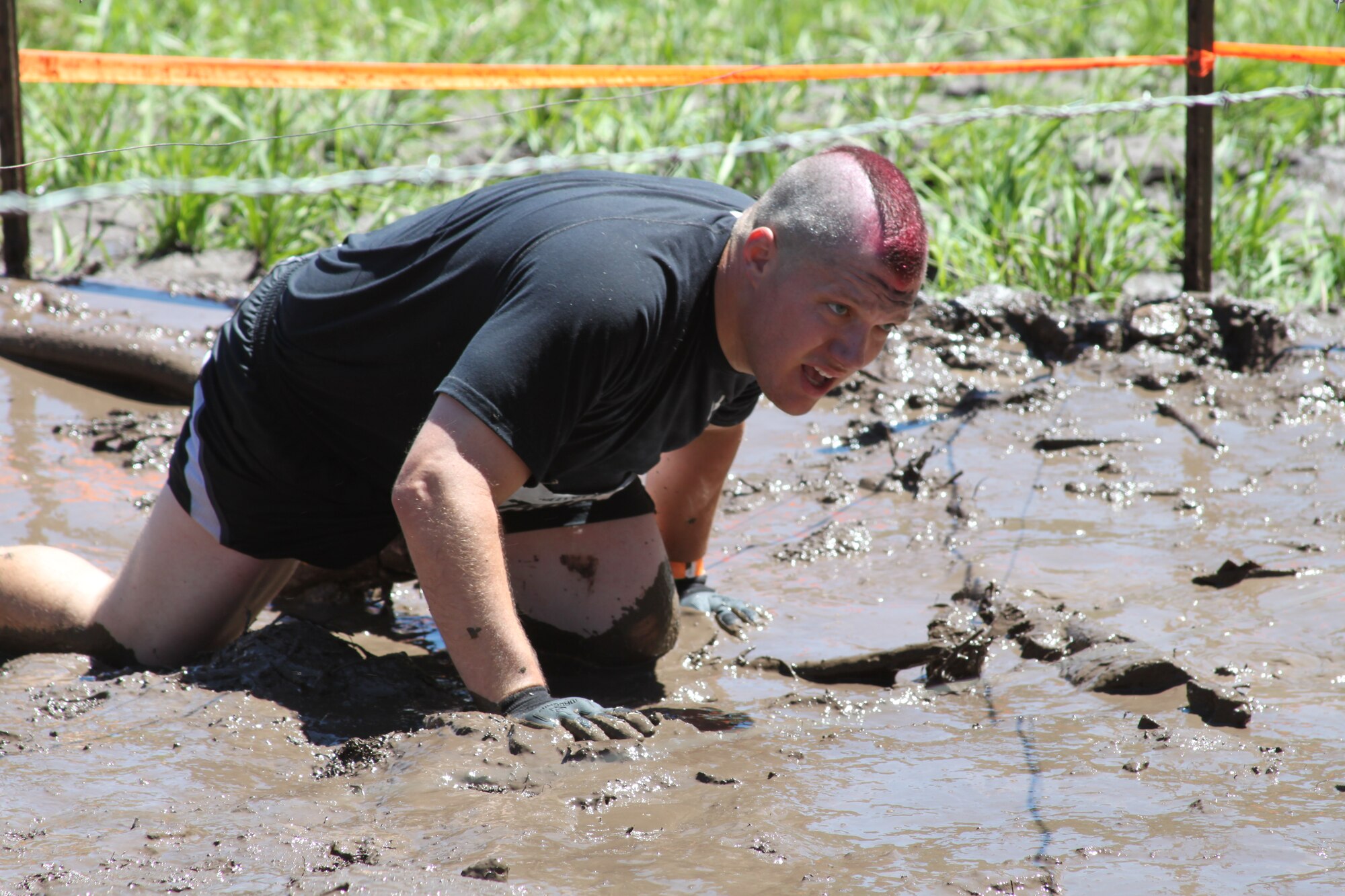 310th Space Wing member Staff Sgt. Aaron Hunt crawls through the Kiss Of Mud obstacle at the Tough Mudder in Avon, Colo. on June 26. Hunt was among a group of seven members of the 310th Mission Support Group to low crawl under barbed wire through the field of mud. (U.S. Air Force photo/Tech. Sgt. Scott P. Farley)