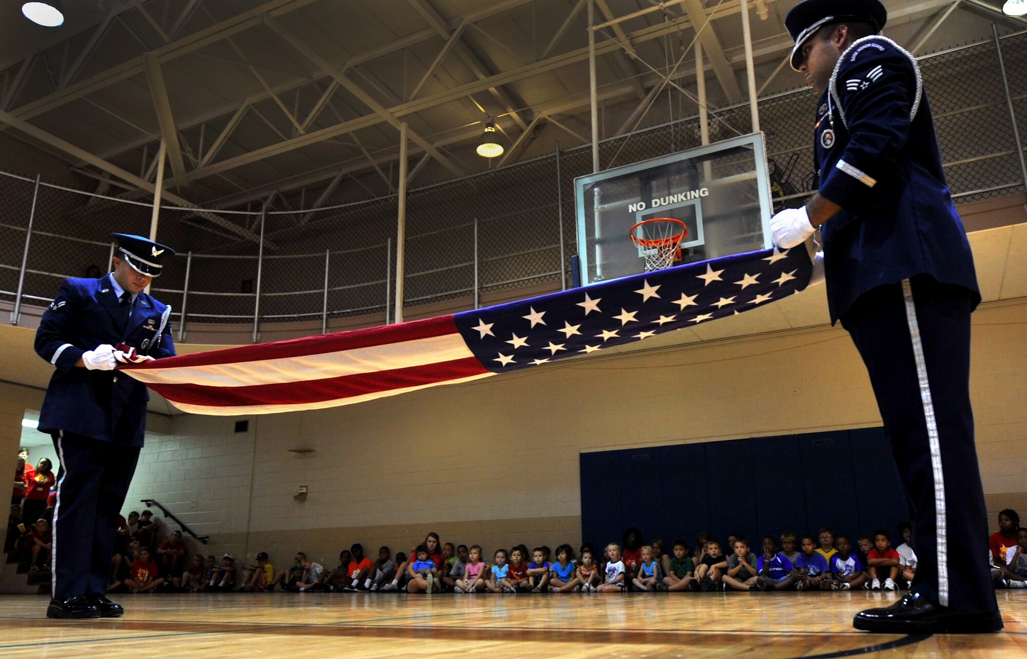 Airman 1st Class Ignacio Livent-Payano, and Senior Airman Taylor Vidinha, Shaw Air Force Base Honor Guard, fold the flag in front of several local youth at the Sumter, S.C., YMCA Aug. 2, 2011.The Shaw Honor Guard performed a flag folding presentation for more than 100 local children to teach them proper flag etiquette. (U.S. Air Force photo by Senior Airman Kenny Holston)(Released)

