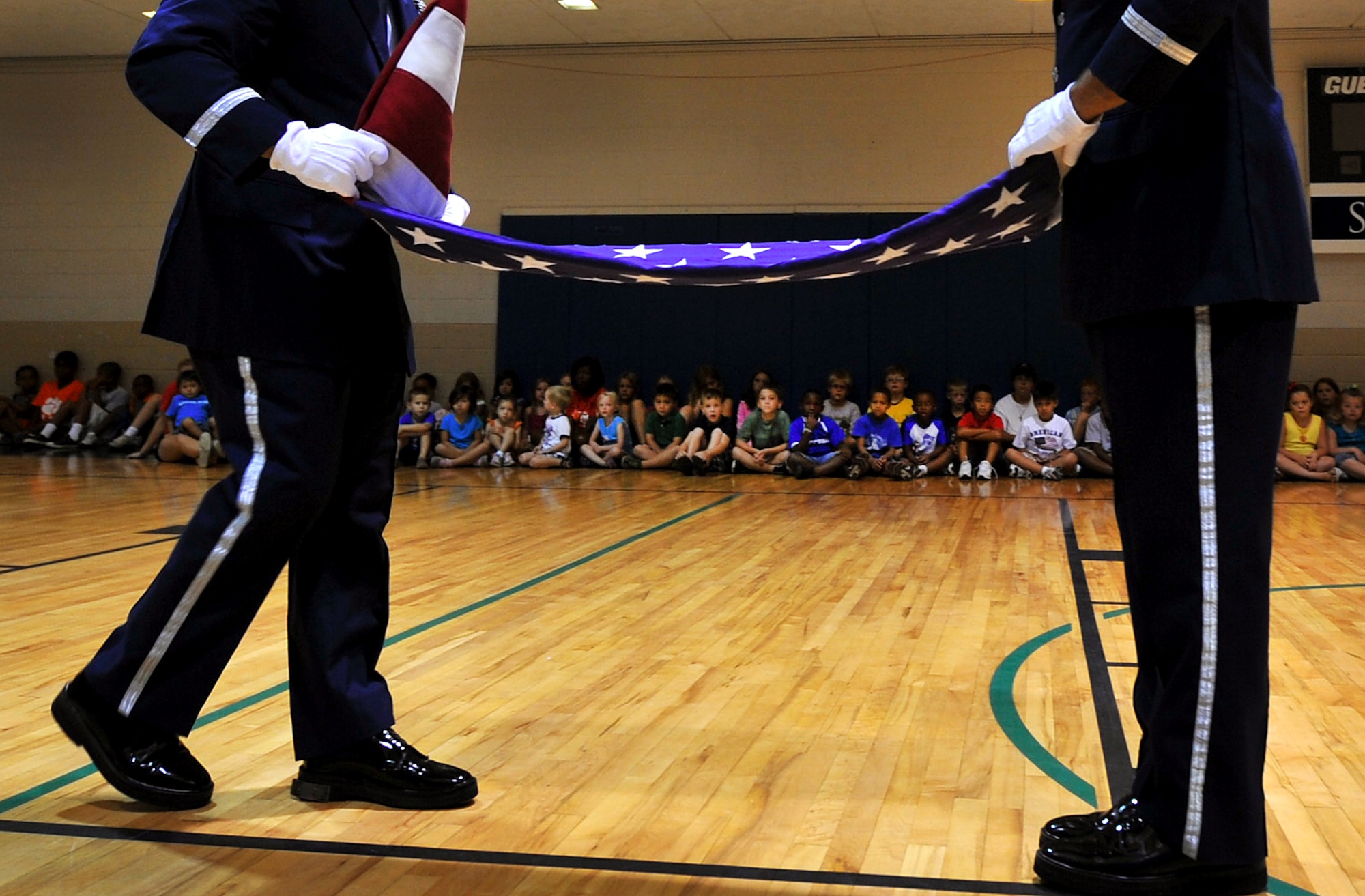 Airman 1st Class Ignacio Livent-Payano, and Senior Airman Taylor Vidinha, Shaw Air Force Base Honor Guard, fold the flag in front of several local youth at the Sumter YMCA Aug. 2, 2011, Sumter S.C. The Shaw Honor Guard performed a flag folding presentation for more than 100 children to teach them proper flag etiquette. (U.S. Air Force photo by Senior Airman Kenny Holston)(Released)

