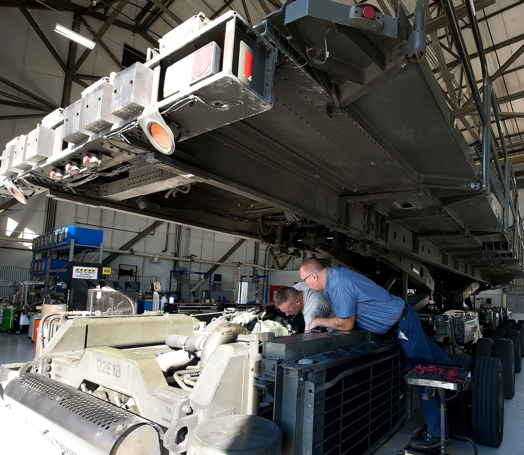 Senior Airman Sammy Anderson (left), a material handling equipment journeyman, and Mike Foxwell, a heavy mobile equipment mechanic, both with the 436th Logistics Readiness Squadron, work on removing the starter from a 60,000 pound cargo loader July 27, 2011, at Dover Air Force Base, Del. The 60K loader is the biggest piece of machinery the material handling equipment maintenance shop works on. (U.S. Air Force photo by Steve Kotecki)