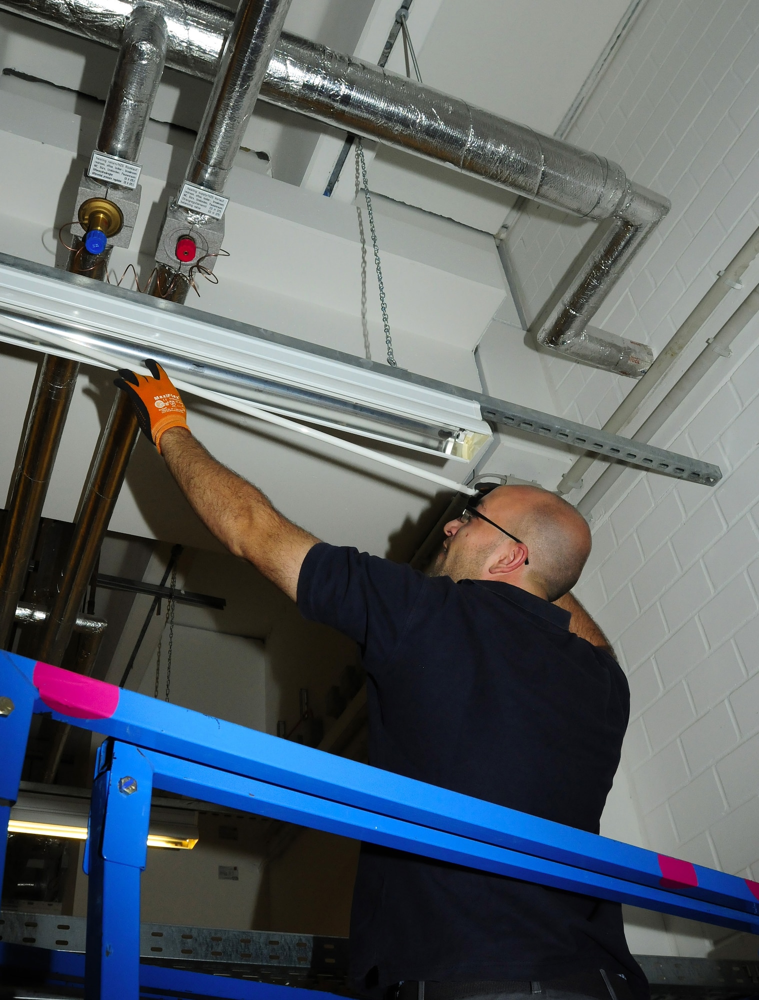 Jonathan Lewandowski, Kaiserslautern Military Community Center heating ventilation and air conditioning technician, helps conserve energy by partially and fully removing light bulbs from key fixtures throughout the facility at Ramstein Air Base, Germany, August 2, 2011. The KMCC recently started "Phase II" of a cost-saving energy initiative that will save at least $15 million over the
course of the building's life. (U.S. Air Force photo by Airman 1st Class Desiree Esposito)