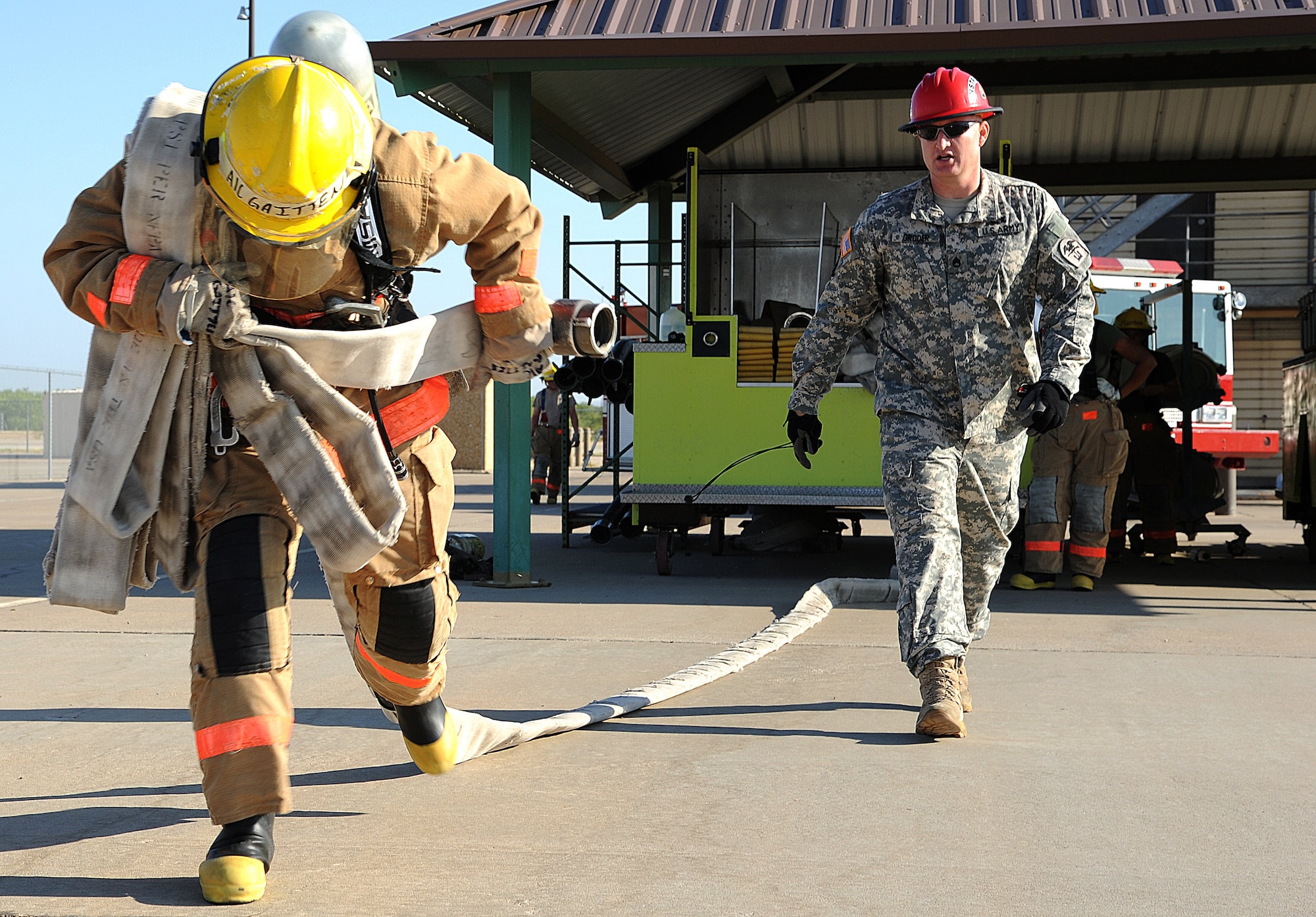 GOODFELLOW AIR FORCE BASE, Texas-- Airman 1st Class Kaleb Gaitten, 312th Training Squadron student, pulls a hose from a fire truck as Staff Sgt. Aaron Groder, 312th Training Squadron instructor, coaches July 28. This drill is used to teach the students that even when fatigue hits, they must remember what they’re taught when it comes to safety procedures. (Air Force photo/ Airman 1st Class Michael Smith)