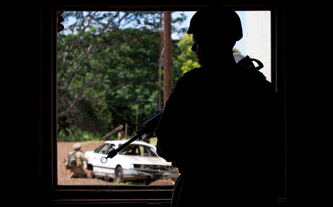 Navy Seaman Nathan Martino, a corpsman with Weapons Company, 3rd Battalion, 3rd Marine Regiment, peers through the window of a building while providing security in a mock Afghan village during counterinsurgency training at Schofield Barracks, Hawaii, Aug. 2, 2011. Over two weeks, 3/3’s line companies rotated from classes to two-day training evolutions at Schofield’s military operations in urban terrain facility, working through scenarios by practicing patrolling, working vehicle control points and interacting with the role-players. Moving further into their pre-deployment training program, the battalion is preparing for the Mojave Viper exercise at Marine Corps Air Ground Combat Center Twentynine Palms, Calif., at the end of August. The month long training event will be their final evaluation before deploying to Afghanistan’s Helmand province in support of Operation Enduring Freedom this fall. Martino is from Old Saybrook, Ct.