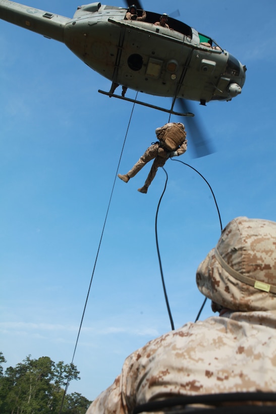 A Marine rappels out of a UH-1N Huey during the Helicopter Rope Suspension Training Masters Course at Landing Zone Vulture on Stone Bay, Aug. 2. The majority of students in the course were from units scheduled to attach and deploy with the 24th Marine Expeditionary Unit in September.