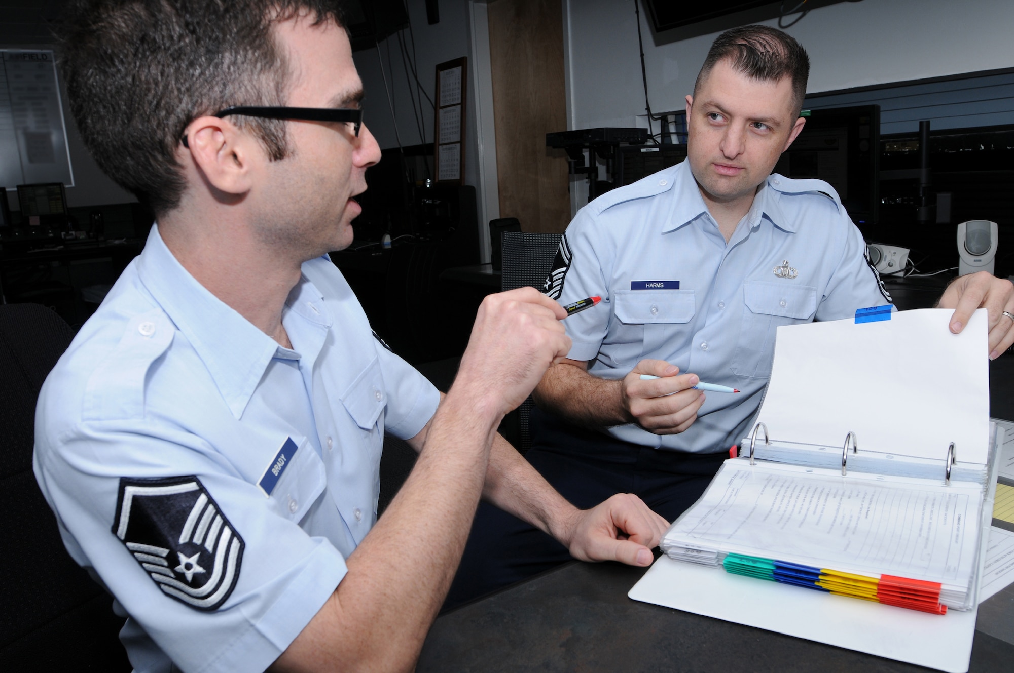 Master Sgt. Joseph Brady, 81st Training Wing command post superintendent, left, and Chief Master Sgt. Brian Harms, 403rd Wing chief of command post, review the Keesler command post quick reaction checklists to stay prepared in the event of an emergency.  (U.S. Air Force photo by Kemberly Groue)