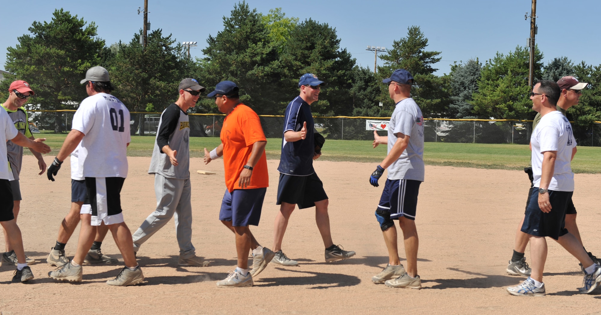 MOUNTAIN HOME AIR FORCE BASE, Idaho  – Team members from the commanders vs. first sergeant’s game of the Operation Warmheart softball tournament slap hands after the last inning of the game here, July 29. The commanders beat the first sergeants 21 to 5. (U.S. Air Force photo by Airman 1st Class Heather Hayward)