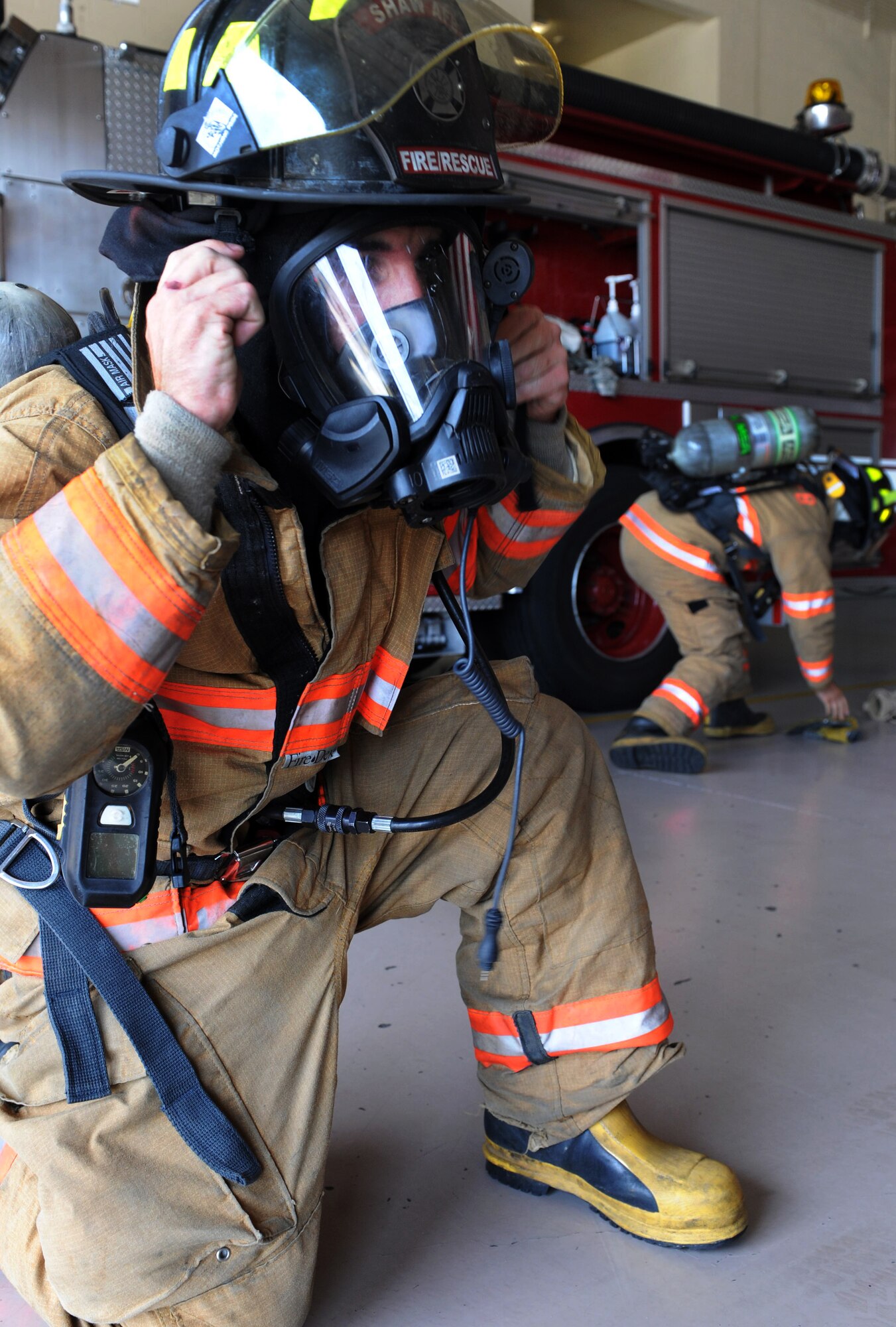 U.S. Air Force Airman 1st Class Danny Thompson, 20th Civil Engineer firefighter, races with fellow firefighters to put on all their gear with the new M-7 Firehawk self-contained breathing apparatus at the fire station Shaw Air Force Base, S.C. Aug. 2, 2011. The new M-7 Firehawk helps Airmen complete the mission by being more durable, safer, user friendly and uses one tank instead of two. The mask has more features which include a voice enhancer and a heads up display that shows how much air is left in the tank. (U.S. Air Force photo/Airman 1st Class Tabatha L. Duarte)(Released)