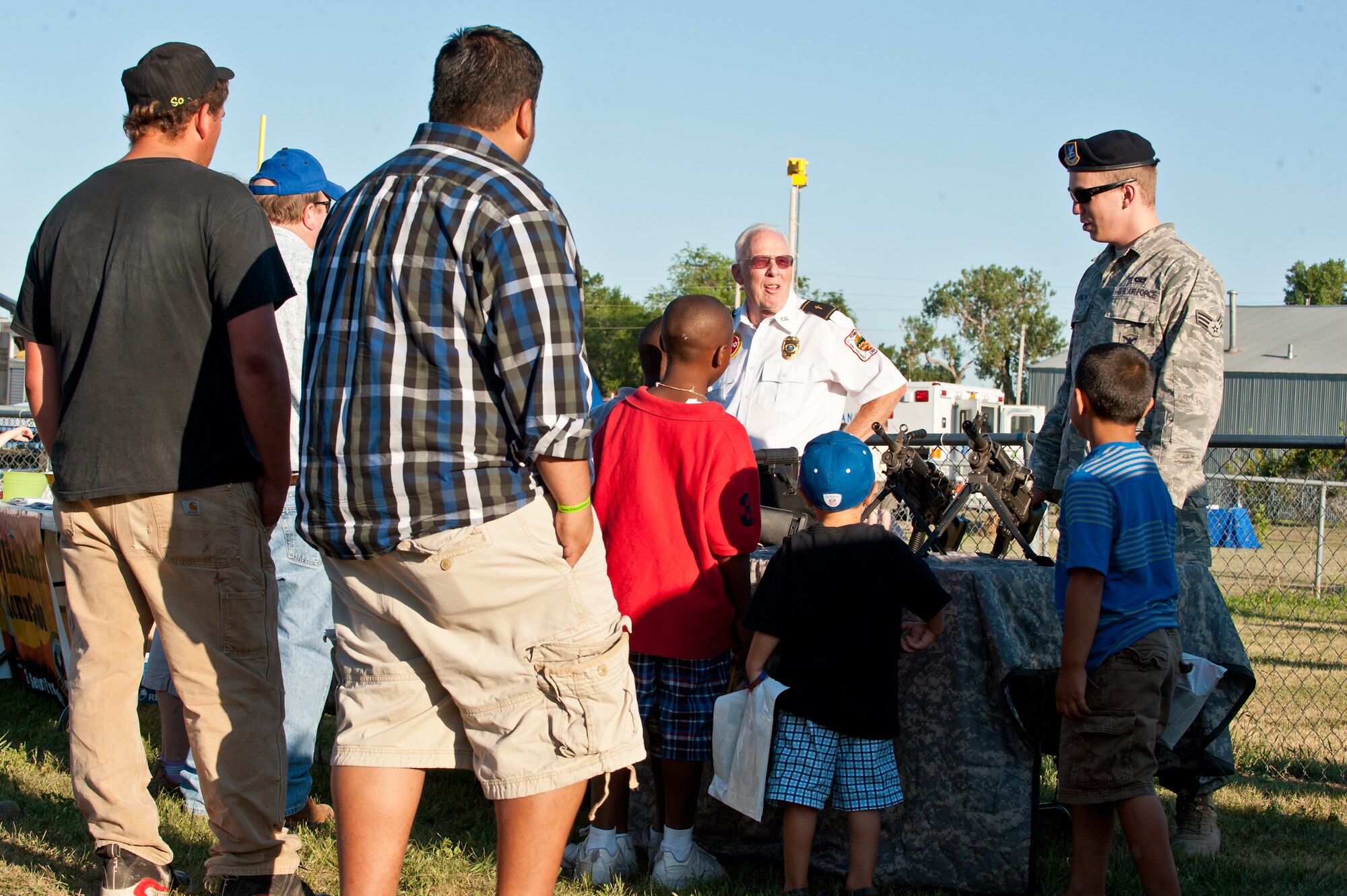 Senior Airman Michael Thompson, 28th Security Forces Squadron armorer, talks with Box Elder residents about the weapons he has on display during a National Night Out event held at the Bandit Ball Field in Box Elder, S.D., Aug. 2, 2011. The event was held to help enhance public safety and prevent crime through awareness and communication. (U.S. Air Force photo/Tech. Sgt. Nathan Gallahan/Released)