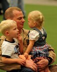 Maj. Frank Welton, 37th Bomb Squadron assistant director of operations, holds his children for the first time in six months at Ellsworth Air Force Base, S.D., July 27, 2011. The 37th BS deployed to Southwest Asia to provide air power to combatant commanders in the U.S. Central Command area of responsibility. (U.S. Air Force photo/Airman Alystria Maurer/Released)