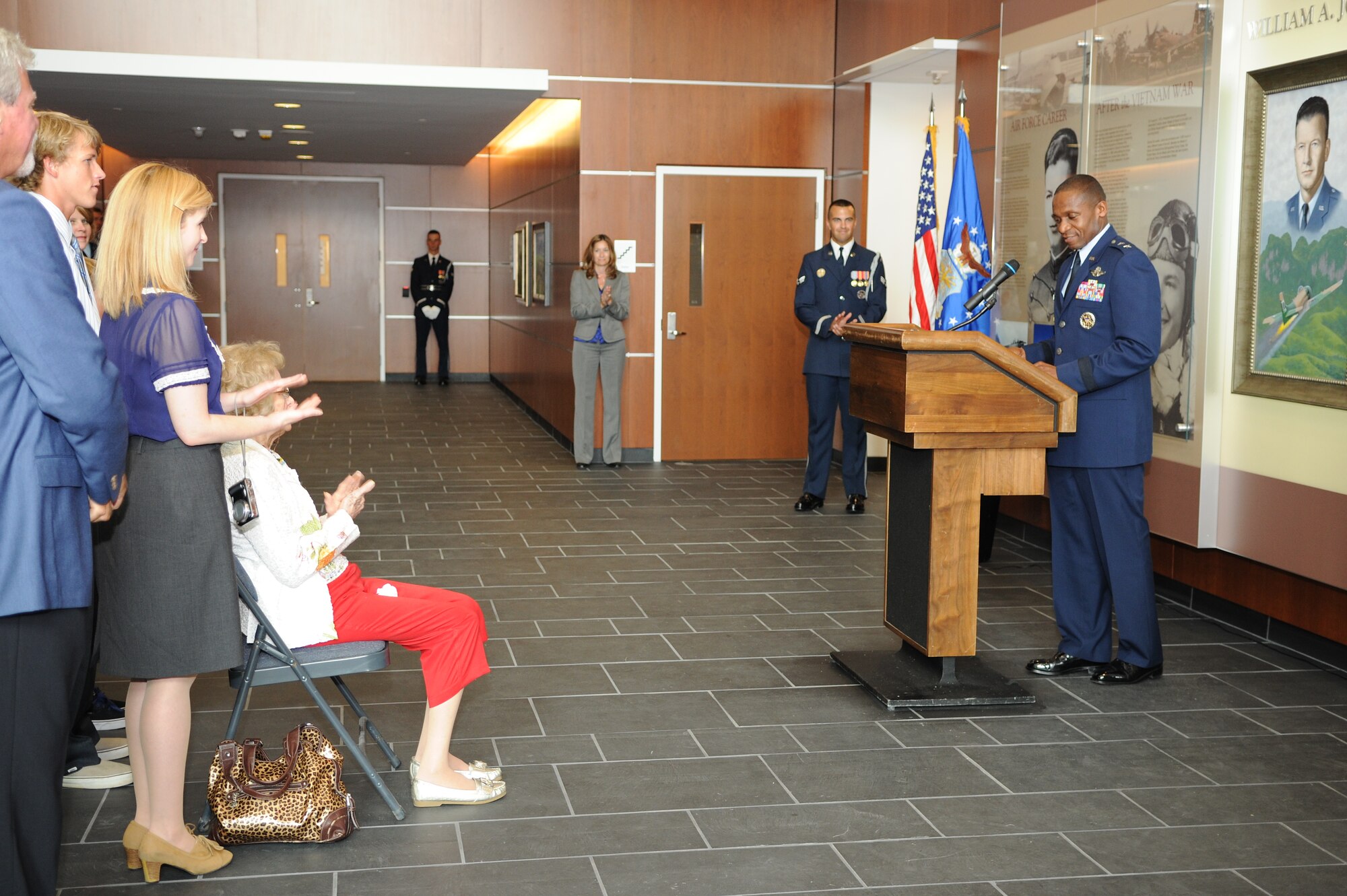Maj. Gen. Darren McDew, Air Force District of Washington commander, speaks in front event attendees, Col. William A. Jones III's widow, Mrs. Lois Jones and other Jones family members at a display dedication in the new William A. Jones III Building on July 28. Jones died in an aircraft accident Nov. 15, 1969 before the Medal of Honor could be presented to him for his selfless heroism. He was 47. His widow received the decoration from President Richard M. Nixon at the White House Aug. 6, 1970. (U.S. Air Force photo/Staff Sgt. Kris Levasseur)