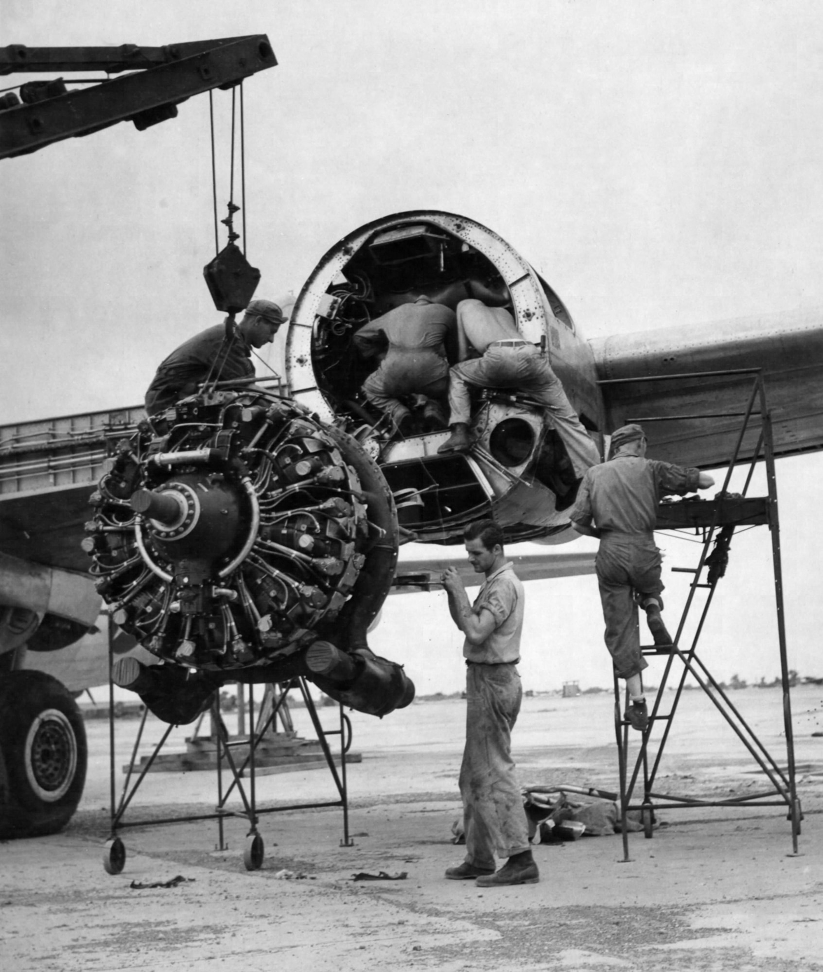 Maintenance personnel in India removing a damaged engine from a B-29.  They took off any undamaged parts and reused them on the replacement engine. (U.S. Air Force photo).