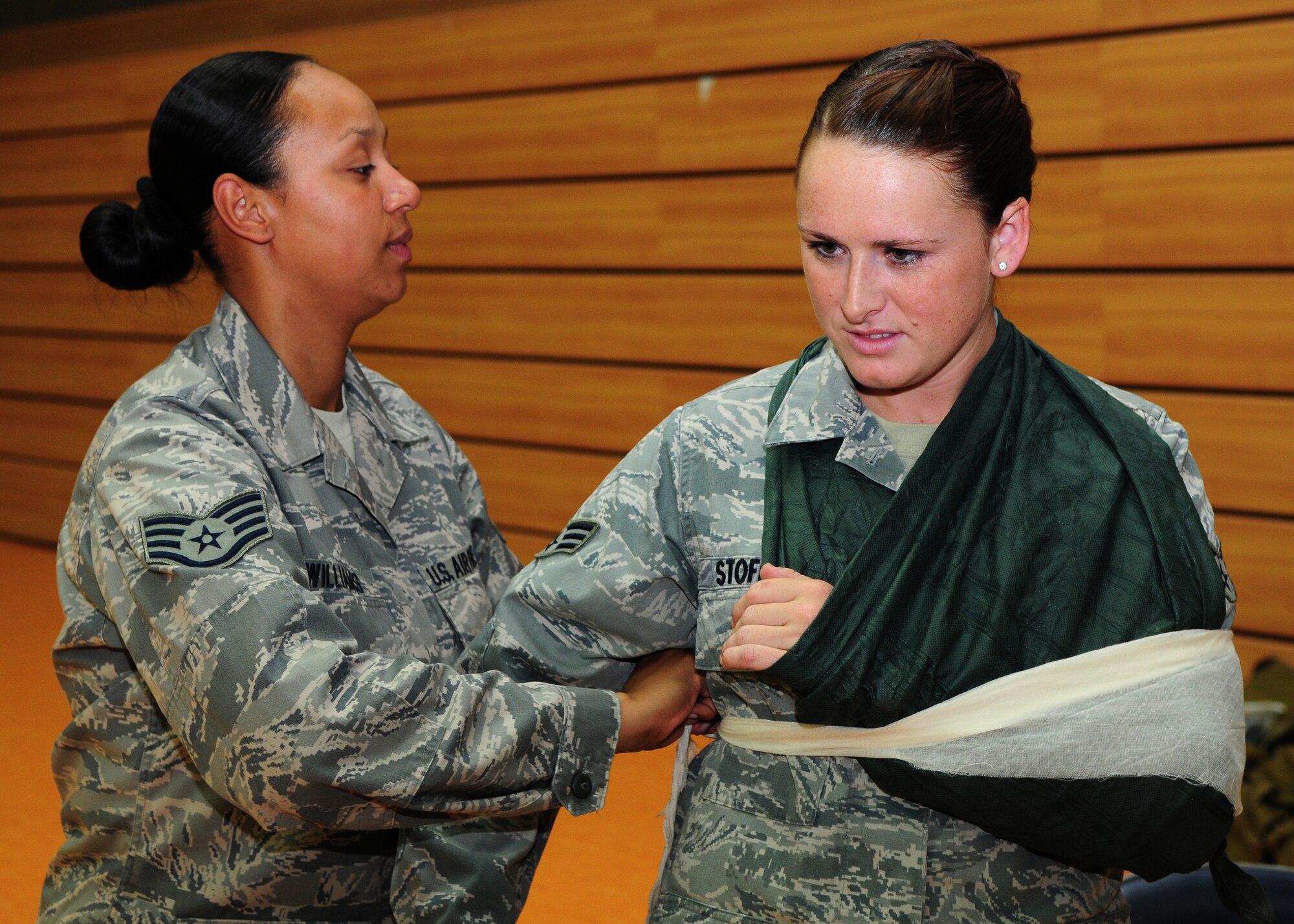 SPANGDAHLEM AIR BASE, Germany – Staff Sgt. Stephanie Williams, 52nd Medical Support Squadron medical administration journeyman, secures a sling to Senior Airman Elena Stofle, 52nd Communication Squadron Airman in charge of official mail, during self aid and buddy care hands-on training here July 28. The training took place to ensure Saber Airmen are prepared for potential deployments, local disasters, humanitarian missions and homeland attacks. (U.S. Air Force photo/Airman 1st Class Matthew B. Fredericks)