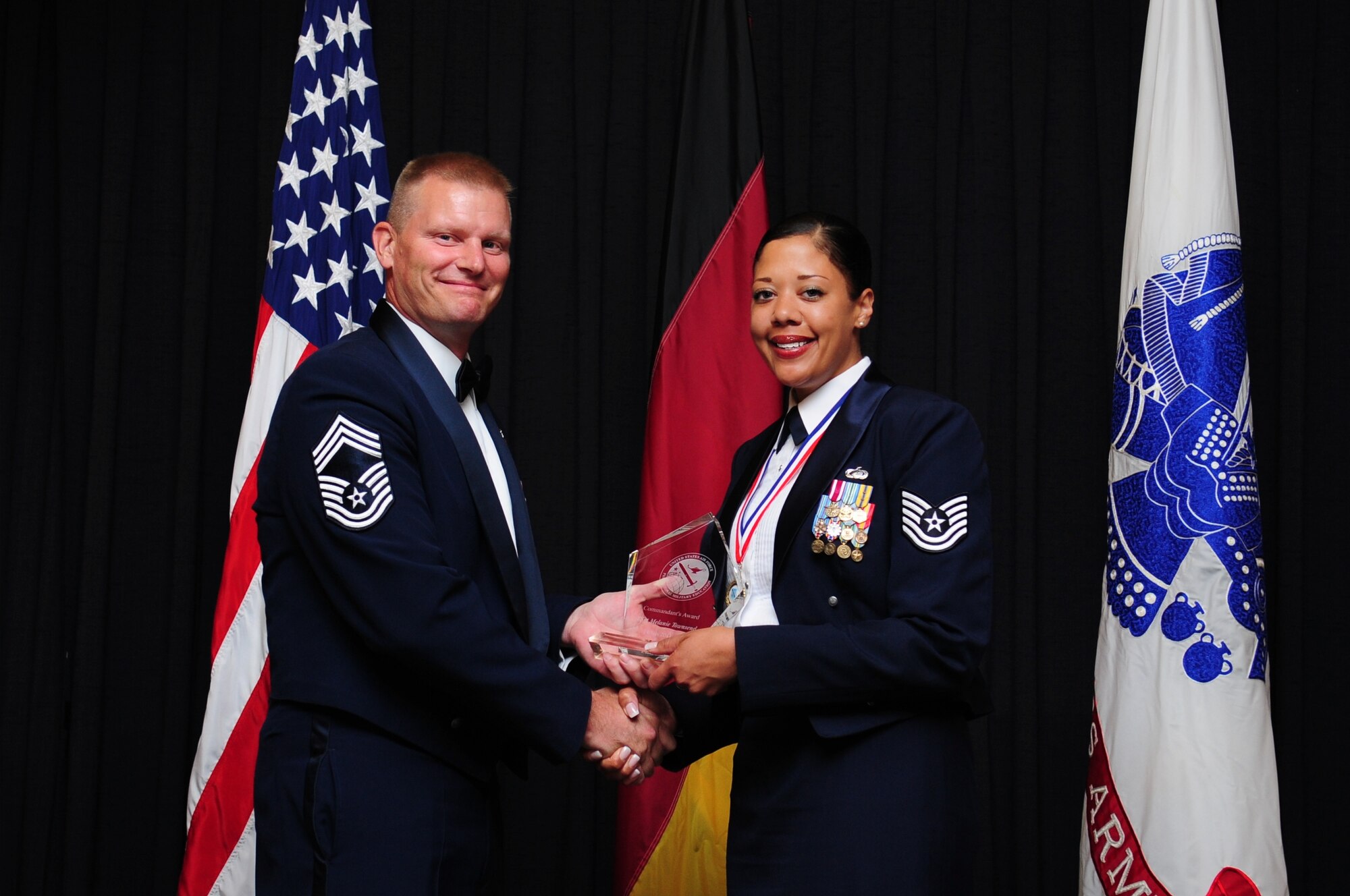 Chief Master Sgt. David Lawrence, Kisling Noncommissioned Officer Academy commandant, presents the Commandant’s Award to Tech. Sgt. Melanie Townsend, from the 39th Comptroller Squadron, July 14, 2011, at Ramstein Air Base, Germany. The Commandant's Award is presented to the student who, in the commandant's judgment, made the most significant contribution to the overall success of the class.  (U.S. Air Force photo by Senior Airman Brittany Perry/Released)
