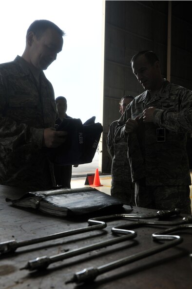 KUNSAN AIR BASE, Republic of Korea -- Master Sgt. Mark Molineaux, 8th Maintenance Squadron phase inspection section, hands Col. Scott Pleus, 8th Fighter Wing commander, a set of overalls here August 2. Col. Pleus visited each section of the Maintenance Group as part as his Immersion tour of the base. (U.S. Air Force photo/Senior Airman Brittany Y. Bateman)