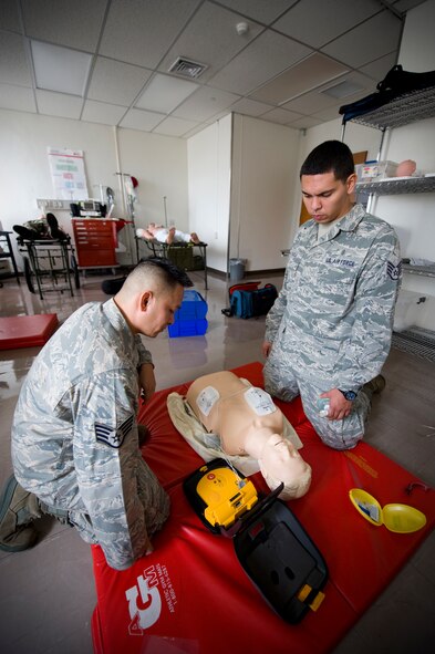 YOKOTA AIR BASE, Japan --  Staff Sgt. Louis Favela, 374th Medical Operations Squadron aerospace medical technician, and Staff Sgt. Don Flores, 374th MDOS program manager and emergency medical technician, perform chest compressions during a demonstration on the steps for using an automated external defibrillator at Yokota Air Base, Japan, Aug. 2, 2011. The AED's electrical contacts are placed on the bare chest of an unconscious victim. From there, the AED gives verbal instructions on what to do next and can potentially play a vital role in saving a life. (U.S. Air Force photo/Staff Sgt Stacy Moless)