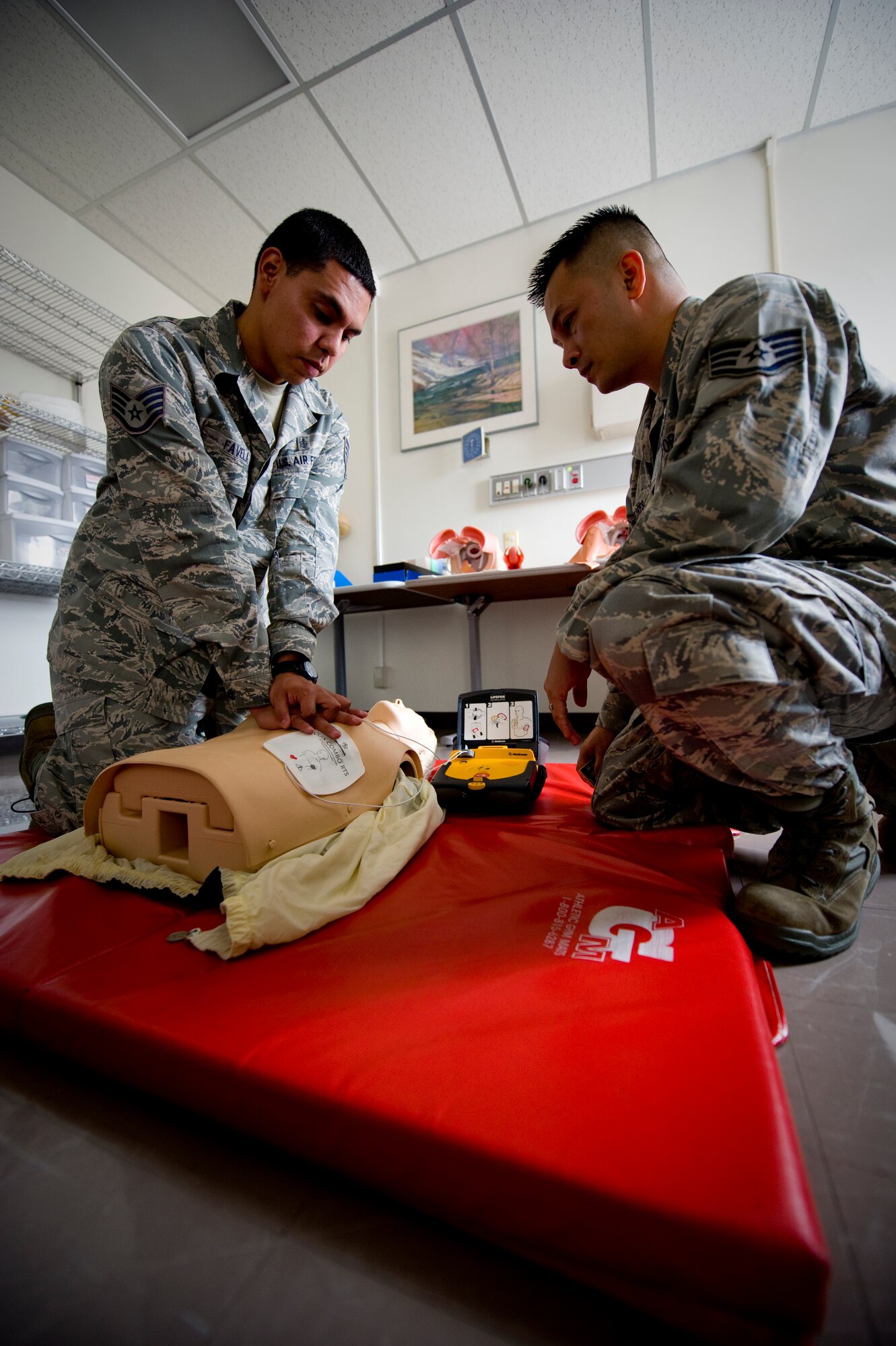 YOKOTA AIR BASE, Japan --  Staff Sgt. Louis Favela, 374th Medical Operations Squadron aerospace medical technician, and Staff Sgt. Don Flores, 374th MDOS program manager and emergency medical technician, perform chest compressions during a demonstration on the steps for using an automated external defibrillator at Yokota Air Base, Japan, Aug. 2, 2011. The AED's electrical contacts are placed on the bare chest of an unconscious victim. From there, the AED gives verbal instructions on what to do next and can potentially play a vital role in saving a life. (U.S. Air Force photo/Staff Sgt Stacy Moless)
