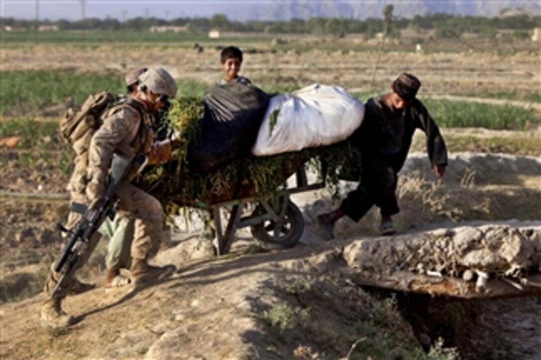 U.S. Marine Corps Cpl. Robert Dominguez helps Afghan children push a wheelbarrow up a slope while conducting a security patrol in Sangin, Afghanistan, on July 22, 2011.  Dominguez is a team leader assigned to Bravo Company, 1st Battalion, 5th Marines, Regimental Combat Team 8.  U.S. Marines conduct patrols to suppress enemy activity and gain the trust of the local populace.  