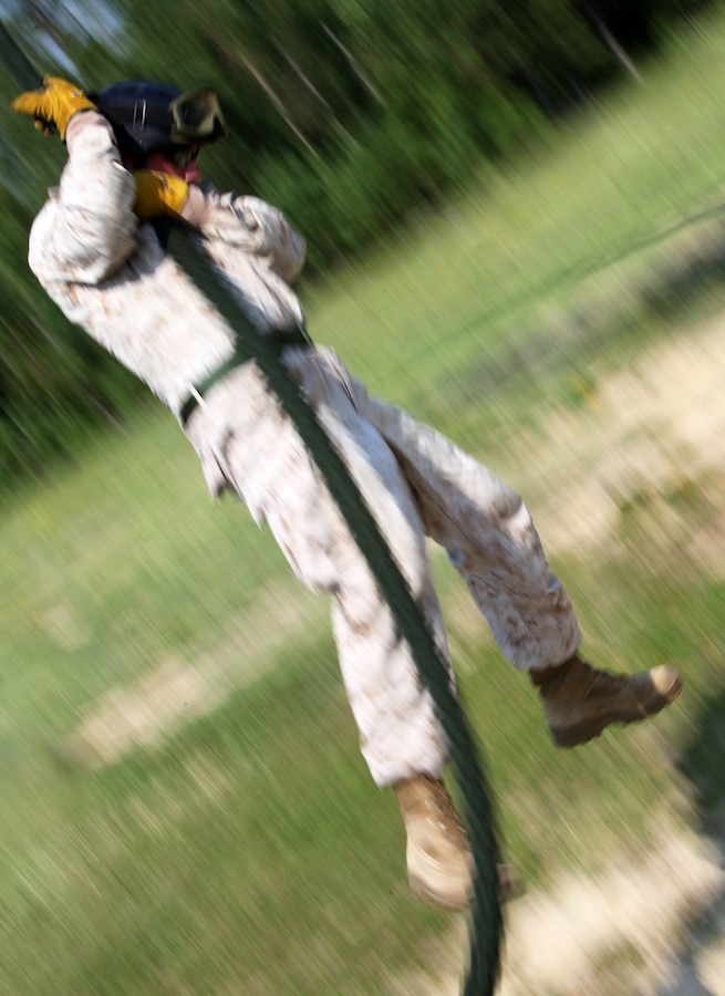 Staff Sgt. Philip Burns, a native of Goshen Ohio and infantry unit leader with Fleet Anti-Terrorism Security Team (FAST), Company Europe, fast ropes off a UH-1N Huey during the Helicopter Rope Suspension Technique Masters Course at Landing Zone Vulture on Stone Bay, Aug. 3. Fast roping is the fastest HRST method Marines use to insert into areas from helicopters.