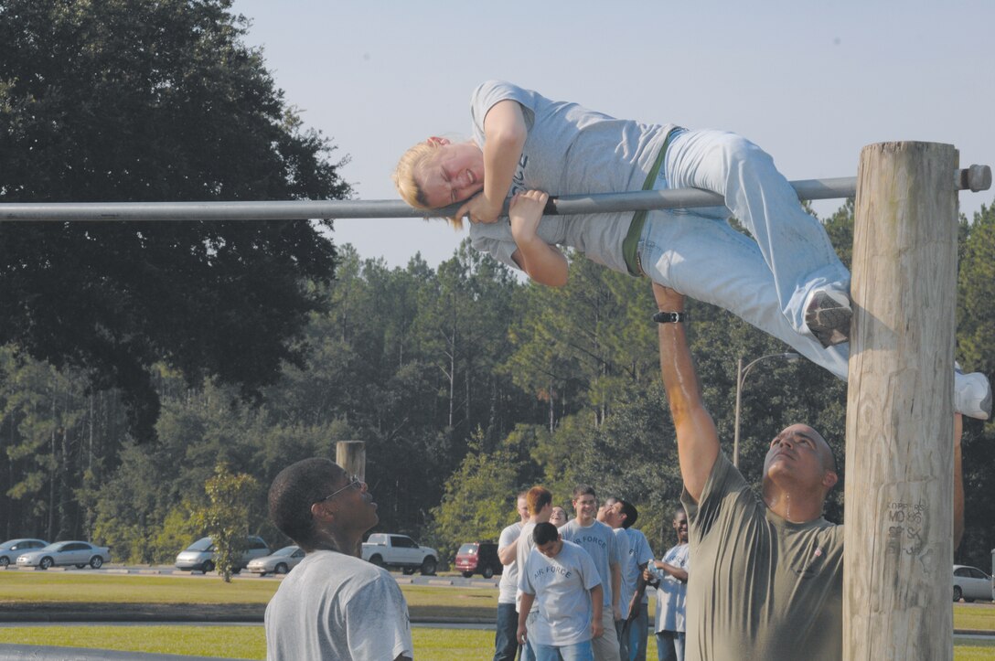 An Air Force Junior Reserve Officers Training Corps cadet struggles to climb over a bar at the Marine Corps Logistics Base Albany obstacle course, Aug. 4. She was assisted by Master Sgt. Mark Carabello. The nearly 70 teenagers, in grades 9-12, were JROTC members from Tift County High School, who were participating in the final leg of their two-week summer leadership training at the base.