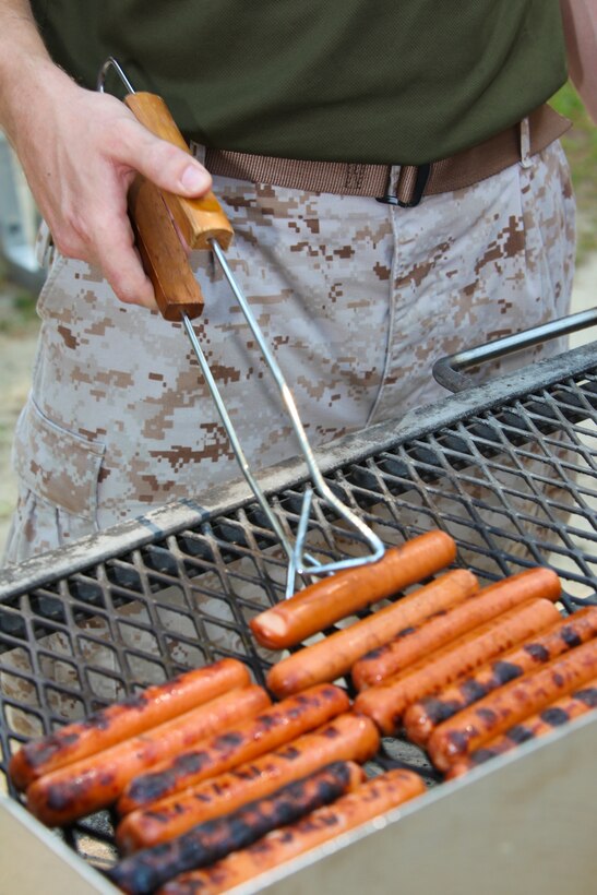 Gunnery Sgt. Michael Kropiewnicki, 26th Marine Expeditionary Unit Combat Camera chief, grills::r::::n::hot dogs for the Marines and sailors of the 26th MEU Command Element during a cigar smoker and::r::::n::barbeque, hosted at the 26th MEU command post, Camp Lejeune, N.C., Aug. 4, 2011. The event::r::::n::was the first time the entire unit spent time together since returning from a eight-and-a-half-month::r::::n::deployment in May. (U.S. Marine Corps photo by Cpl. Christopher Stone)