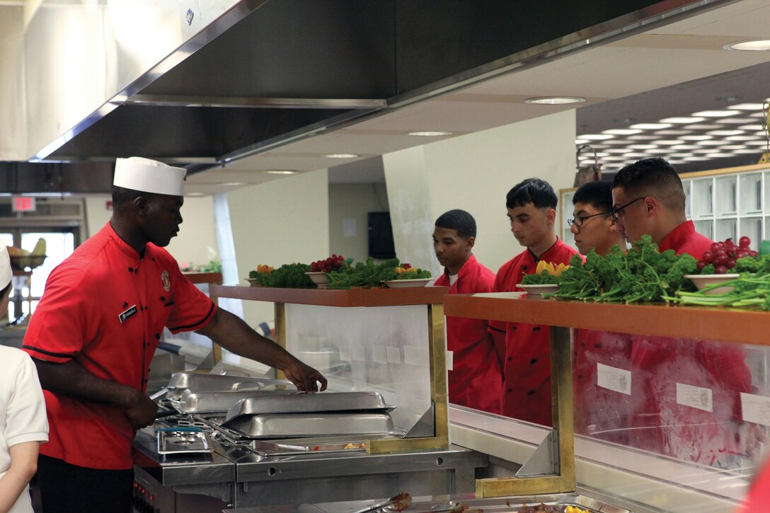 Sgt. Londell D. Calloway, chief cook for Headquarters and Headquarters Squadron, Marine Corps Air Station Futenma mess hall performs a line critique to remind the Marines of the portion sizes and point out any discrepancies with the products Aug. 4. Futenma’s mess hall was recently awarded Mess Hall of the Year for Marine Corps Bases Japan.::r::::n::