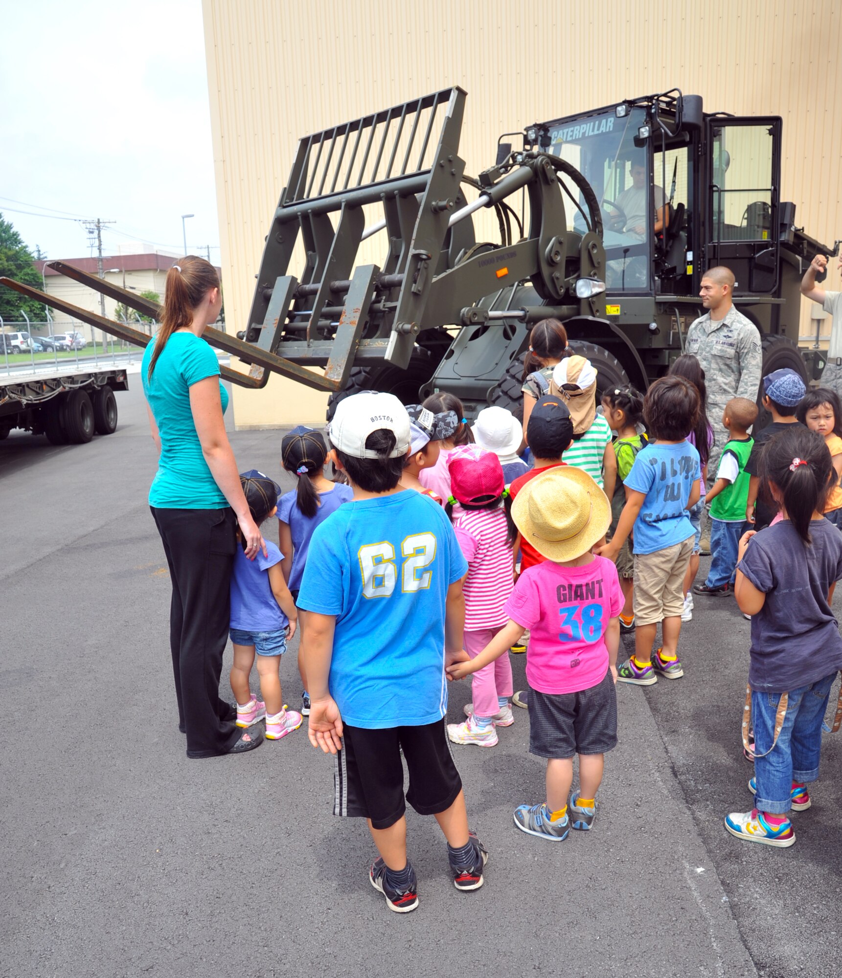 YOKOTA AIR BASE, Japan -- Students from Caesar's Creek School in Hanno, Japan watch Airman 1st Class Adam Caton, 374th Logistics Readiness Squadron air transportation specialist, operate an altering fork lift at Yokota Air Base, Japan, August 2, 2011. The students were given a tour through the combat mobility flight shop as an opportunity to interact with Yokota Airmen.  (U.S. Air Force photo/Airman 1st Class Krystal M. Garrett)  