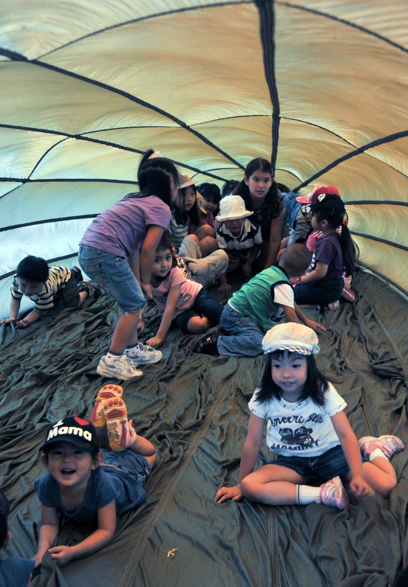 YOKOTA AIR BASE, Japan -- Students from Caesar's Creek School in Hanno, Japan, play inside of a blown up G-12 E parachute at Yokota Air Base, Japan, August 2, 2011. Senior Airman Matthew Brewer, 374th Logistics Readiness Squadron, explained different aspects of his job to the students during their tour of the combat mobility flight shop. (U.S. Air Force photo/Airman 1st Class Krystal M. Garrett)
