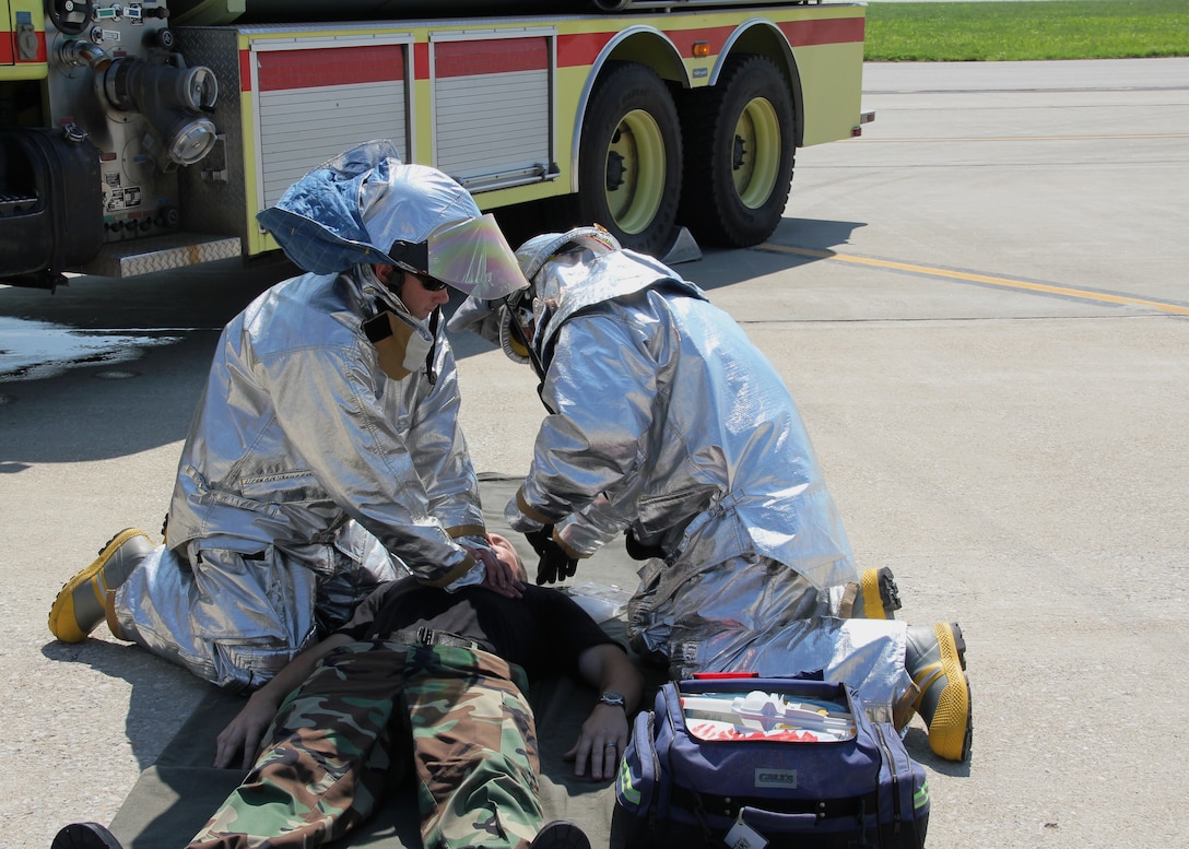 Firefighters from the 932nd Civil Engineer Squadron perform first aid to a "sick" crew chief on the flightline during a training exercise.  The drill included using two fire trucks, fire suppression and a search and rescue operation. The egress proficiency training is held at least twice a year on the C-9C aircraft, said Master Sgt. Reginald Moore, assistant chief of firefighter training.  The 932nd CES firefighters also perform egress training on the C-40C.  The 932nd Airlift Wing is the only Air Force Reserve flying unit that flies the C-40C and C-9C.  (U.S. Air Force photo/Tech. Sgt. Gerald Sonnenberg)
