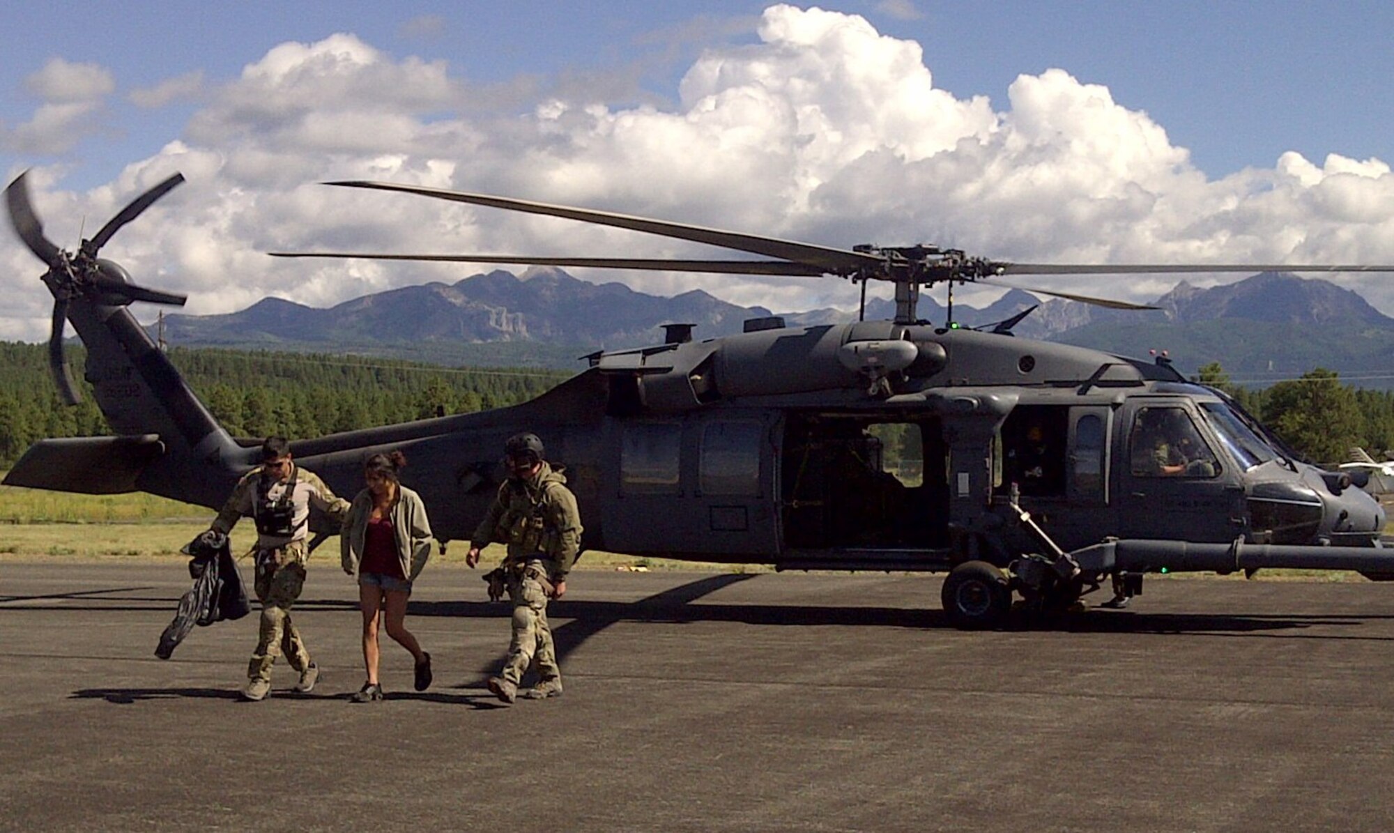KIRTLAND AIR FORCE BASE, N.M. -- Staff Sgts. Mark Houghton (left) and Scott Dowd, pararescuemen from Detachment 1, 342nd Training Squadron,  escort Lashaye Westbrook (center) from the HH-60 Pave Hawk used in the recovery to the waiting ambulance at Archuleta County Airport at Stevens Field in Pagosa Springs, Colo., Monday. Westbrook, a Farmington, N.M., native, become separated from a group hiking near Pagosa Springs Saturday. She was stranded for two days without shelter, food and water, and endured rain along with overnight low temperatures in the 40s. (Courtesy photo)