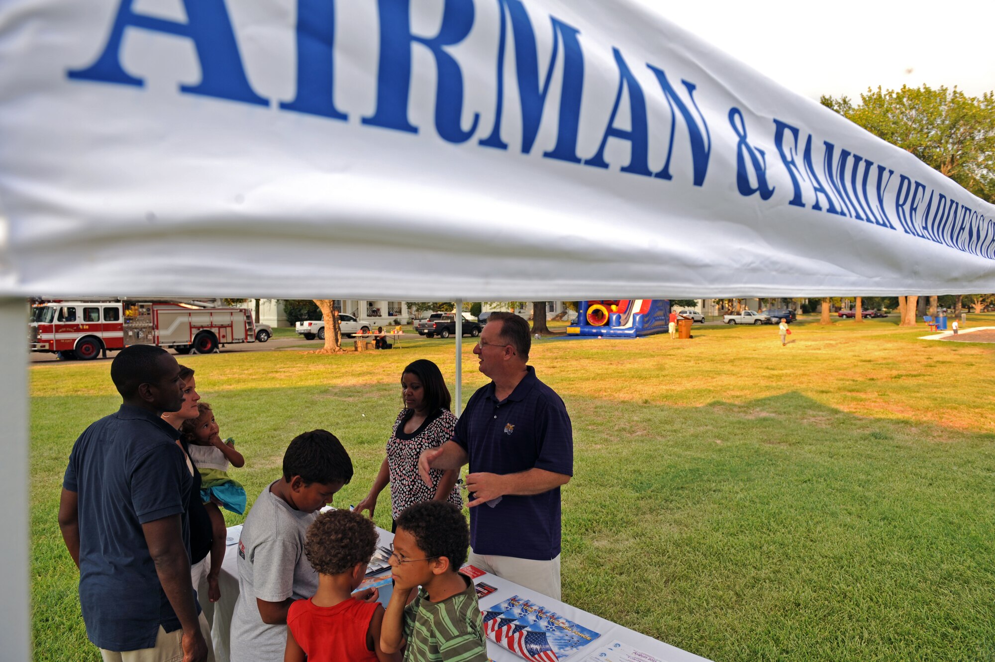 Charlotte Hikes, community readiness technician, and Master Sgt. Frank Deviller, Airman and Family Readiness Center superintendant, tell the Raybon family about programs the AFRC provides during the fourth annual National Night Out on Barksdale Air Force Base, La., Aug. 2. Several organizations collaborated for the event to increase police awareness and fire prevention education. (U.S. Air Force photo/Airman 1st Class Micaiah Anthony)(RELEASED)