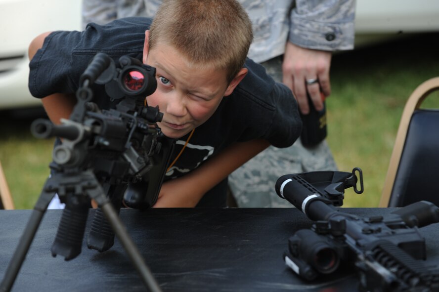Davin Wilson,10, looks through an M-68 close combat optic attached to an M-249 light machine gun during the fourth annual National Night Out on Barksdale Air Force Base, La., Aug. 2. The 2nd Security Forces Squadron brought out three M-4 carbines, an M-24 sniper rifle and an M-249 light machine gun. All weapons on display had the bolt and bolt carrier group removed to prevent them from firing. (U.S. Air Force photo/Airman 1st Class Micaiah Anthony)(RELEASED)