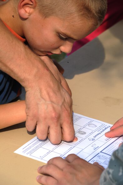 Staff Sgt. Kevin Smith, 2nd Maintenance Squadron, helps his son Braydon Smith, 6, make fingerprints for a Child Identification Kit during the fourth annual National Night Out on Barksdale Air Force Base, La., Aug. 2. The Child Identification Kit helps identify lost or missing children. (U.S. Air Force photo/Airman 1st Class Micaiah Anthony)(RELEASED)