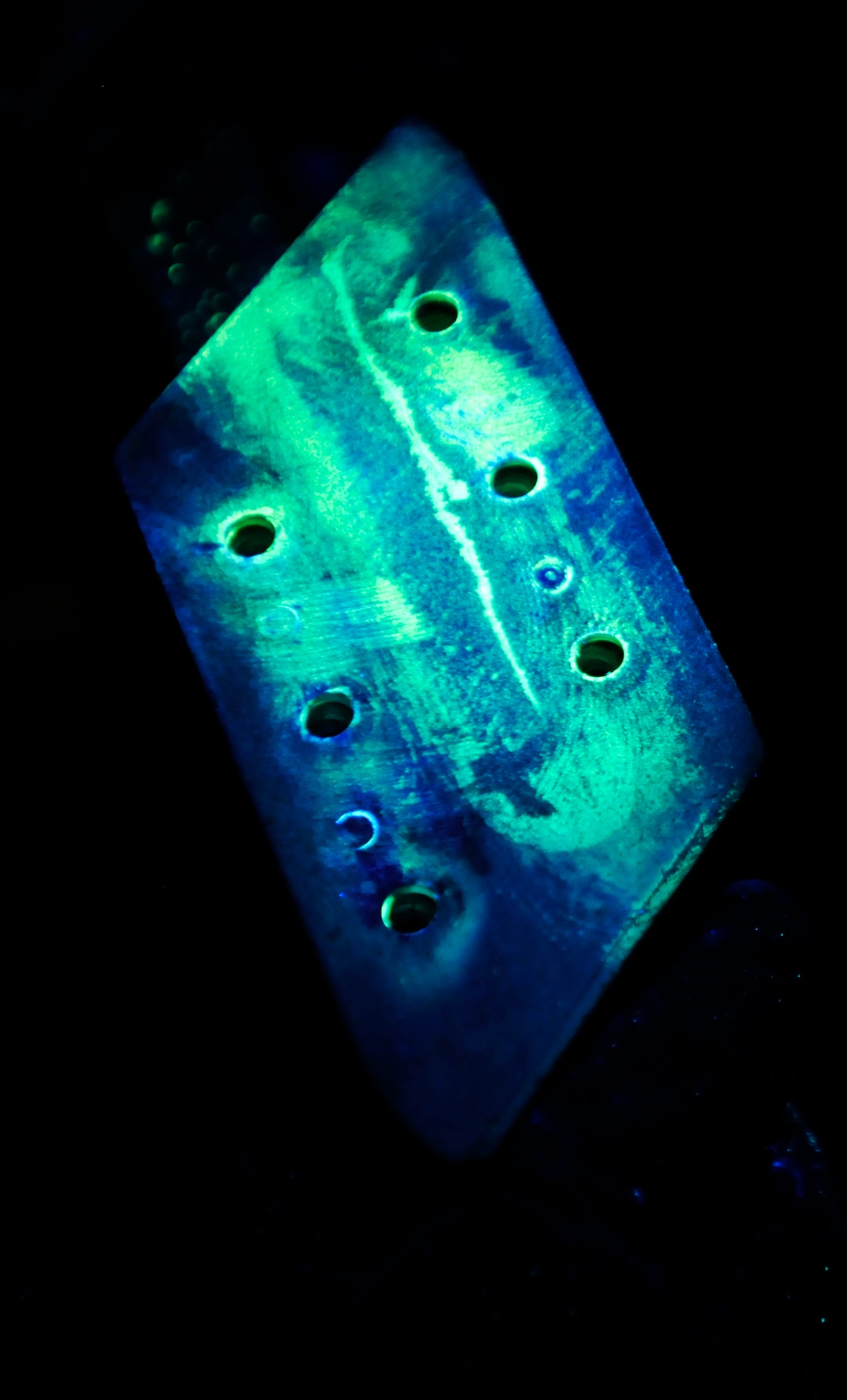 ROYAL AIR FORCE LAKENHEATH, England - After being cleaned and painted with fluorescent penetrant, an aircraft part is inspected under ultraviolet light for flaws by Nondestructive Inspection specialists at RAF Lakenheath, Aug. 2, 2011. Airmen from the NDI are responsible for finding the smallest aircraft defects so they can be repaired before they become a larger problem. (U.S. Air Force photo/Senior Airman Tiffany M. Deuel)