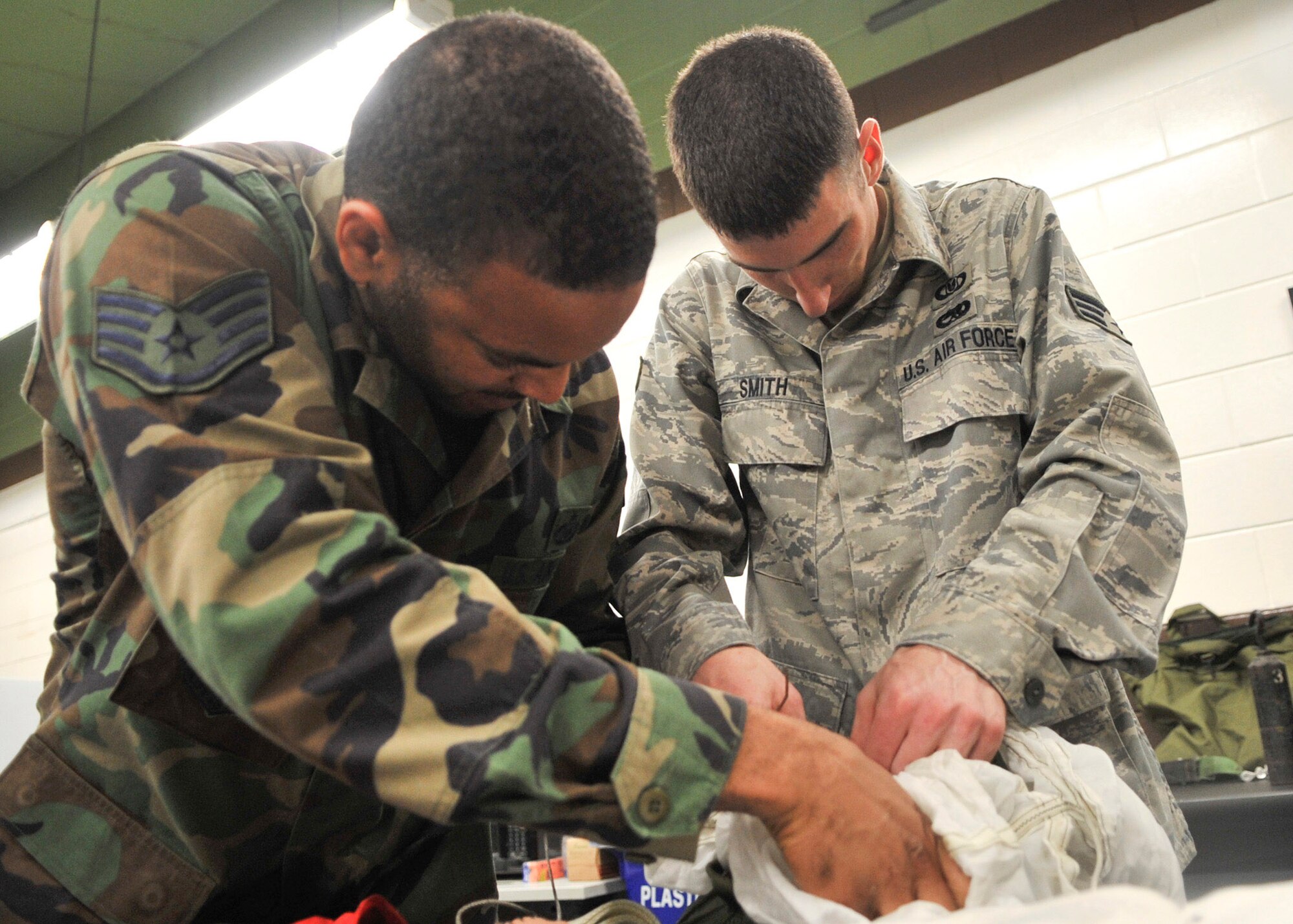 (Let) Staff Sgt. Louis Boyd, 51st Operation Support Squadron air crew flight equipment craftsman and Senior Airman Ryan Smith, 51st Operation Support Squadron air crew flight equipment journeymen, both apply pressure to close a de-acceleration canopy. The canopy weighs about 40 pounds and is on a 60 day inspection cycle. (U.S. Air Force Photos by/ Senior Airman Adam Grant)        