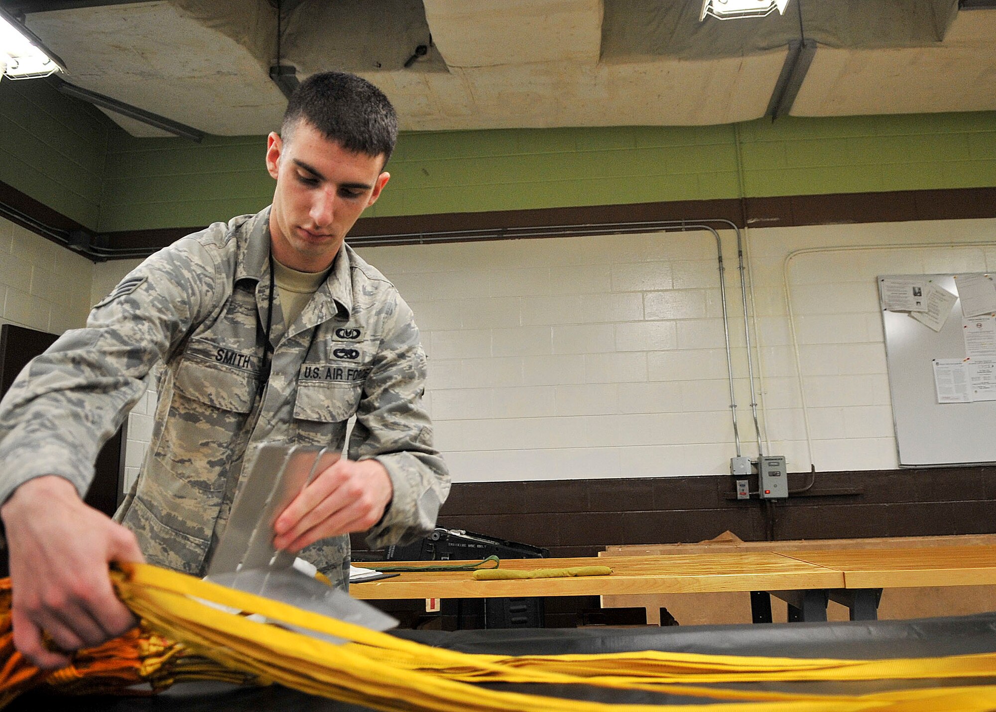 Senior Airman Ryan Smith, 51st Operation Support Squadron air crew flight equipment journeymen, aligns the suspension line of a de-acceleration canopy. The canopy will be used as a second line of protection to slow down the Republic of Korea’s F-4 fighter plane in case of emergency where the main brakes malfunction. (U.S. Air Force Photos by/ Senior Airman Adam Grant)
