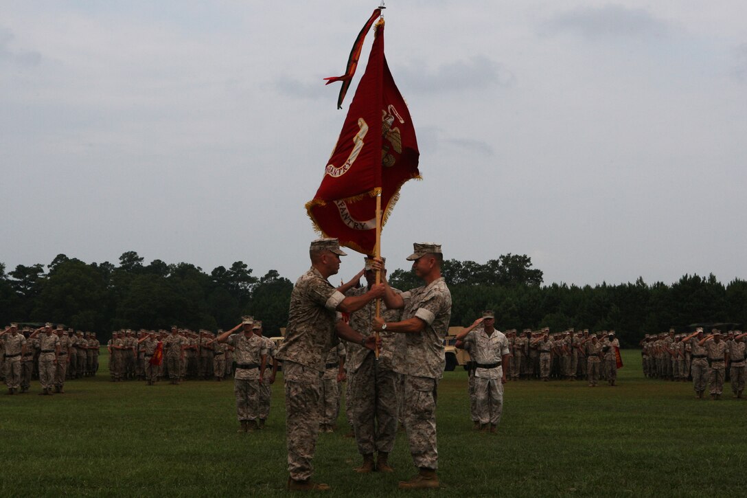 Col. Timothy S. Mundy (right), outgoing commanding officer of School of Infantry - East, passes the colors to Col. Barry J. Fitzpatrick during the SOI-EAST change of command ceremony aboard Camp Geiger, Aug. 5. Fitzpatrick is coming into command following a year-long deployment with I Marine Expeditionary Force (Forward) while Mundy is assigned to 2nd Marine Division.