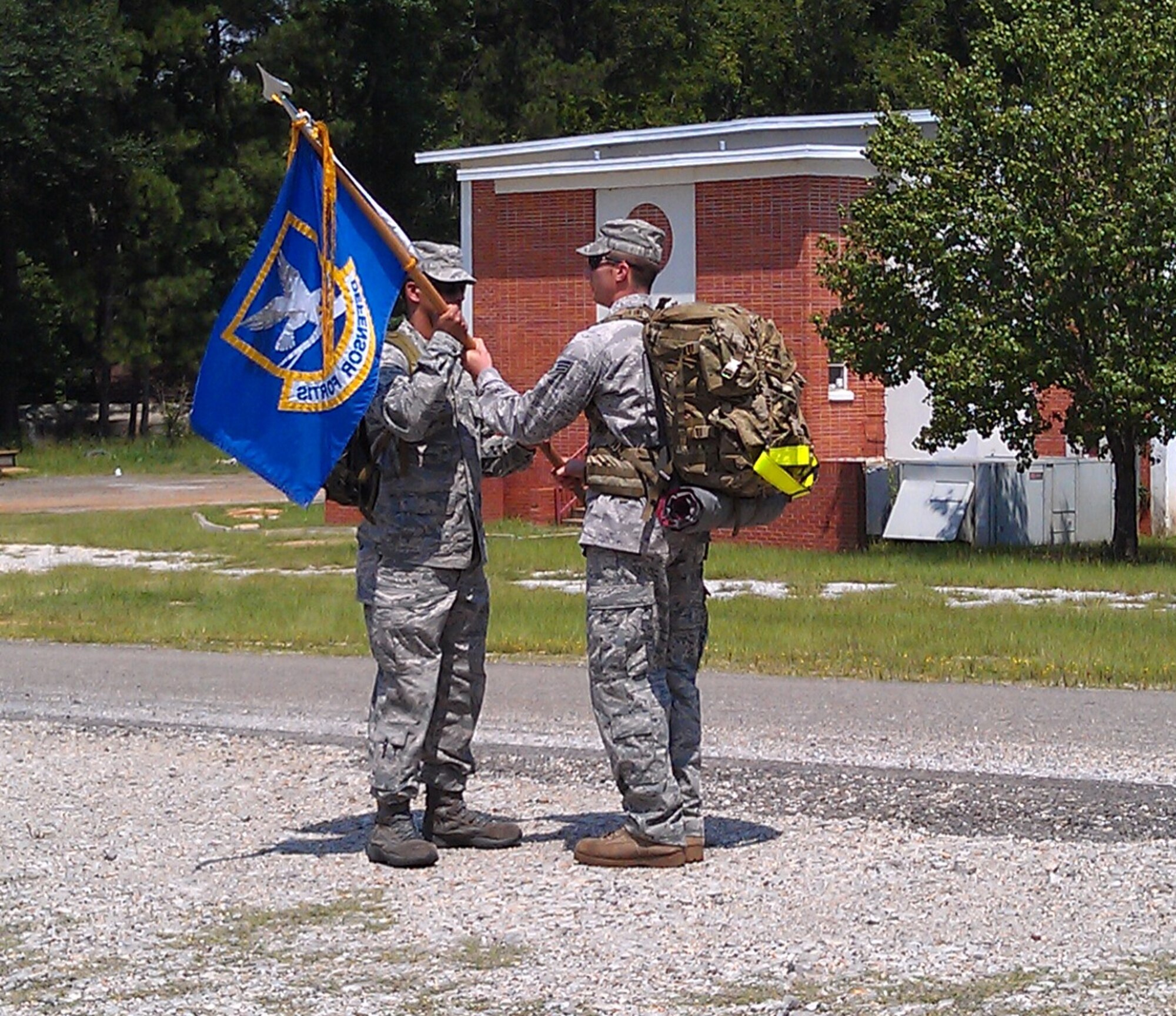 Senior Airman Allen Buning, 1st Special Operations Security Forces Squadron, left, passes a guidon to a member of 325th SFS's team from Tyndall Air Force Base, Fla., at Gilbertown, Ala., Aug. 1, 2011. The 325th SFS team assumes responsibility for keeping the Ruck March to Remember on schedule for a projected arrival at Ground Zero in New York City, N.Y., on the 10th anniversary of 9/11.  (Courtesy photo)