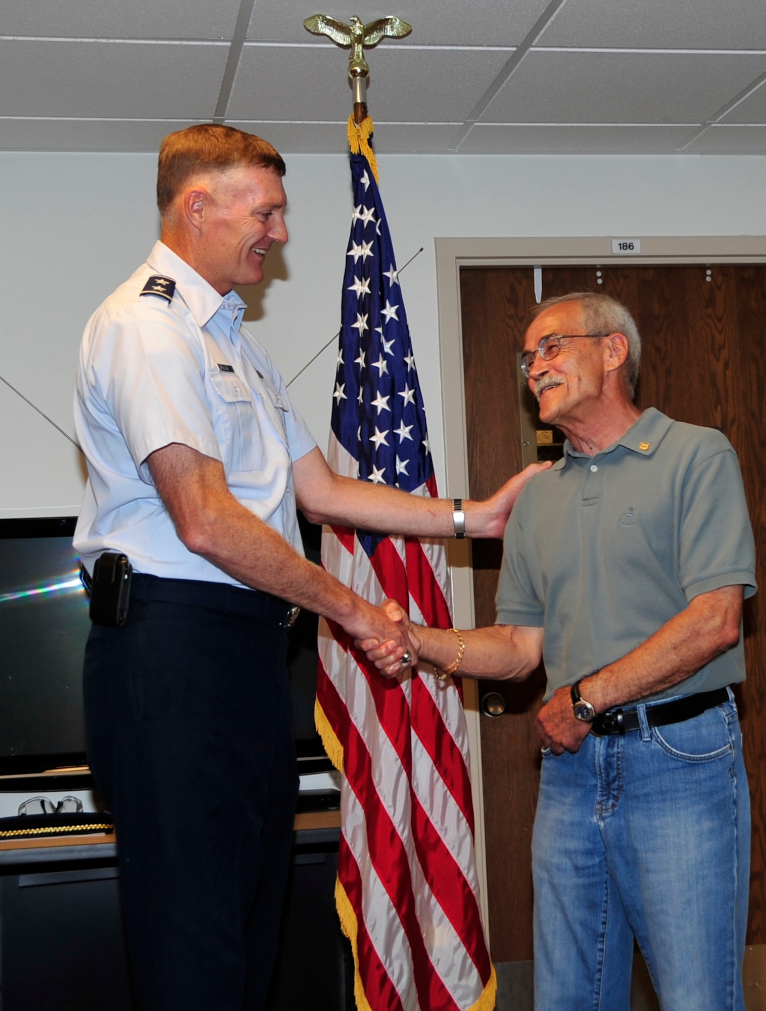 Maj. Gen. Andrew Busch, commander of the Ogden Air Logistics Center, congratulates Rafat "Ray" Ibrahim on his 50 years of service at a ceremony Aug. 1. Ibrahim works as an industrial hygienist, counterpart to a bioenvironmental engineer, for the 75th Aerospace Medicine Squadron. (U.S. Air Force photo by Kim Cook)