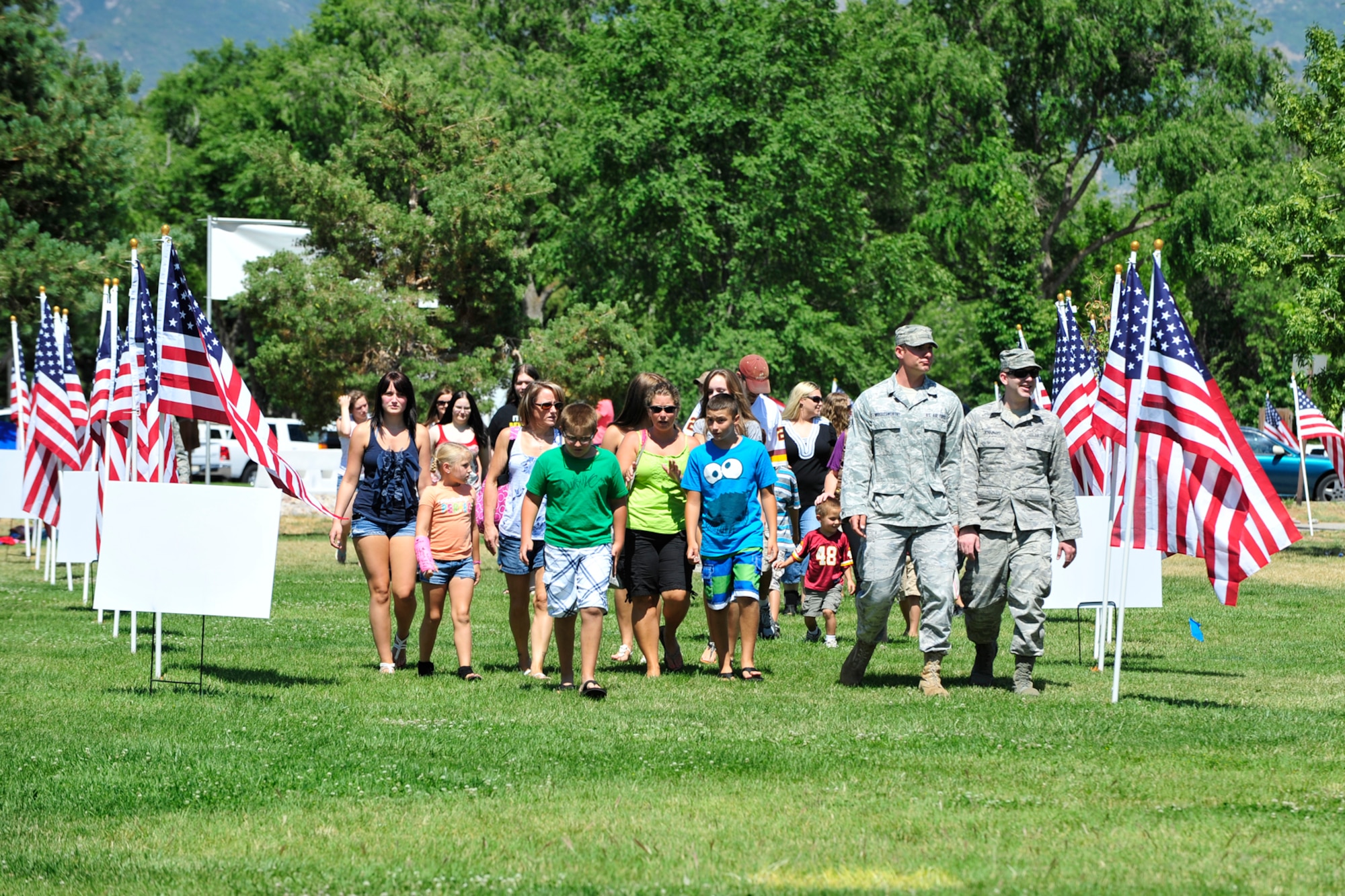 Military family members and Airmen walk through the flag-lined entrance to the Salute to the Nation's Defenders Picnic July 29 at Centennial Park. (U.S. Air Force photo by Kim Cook)